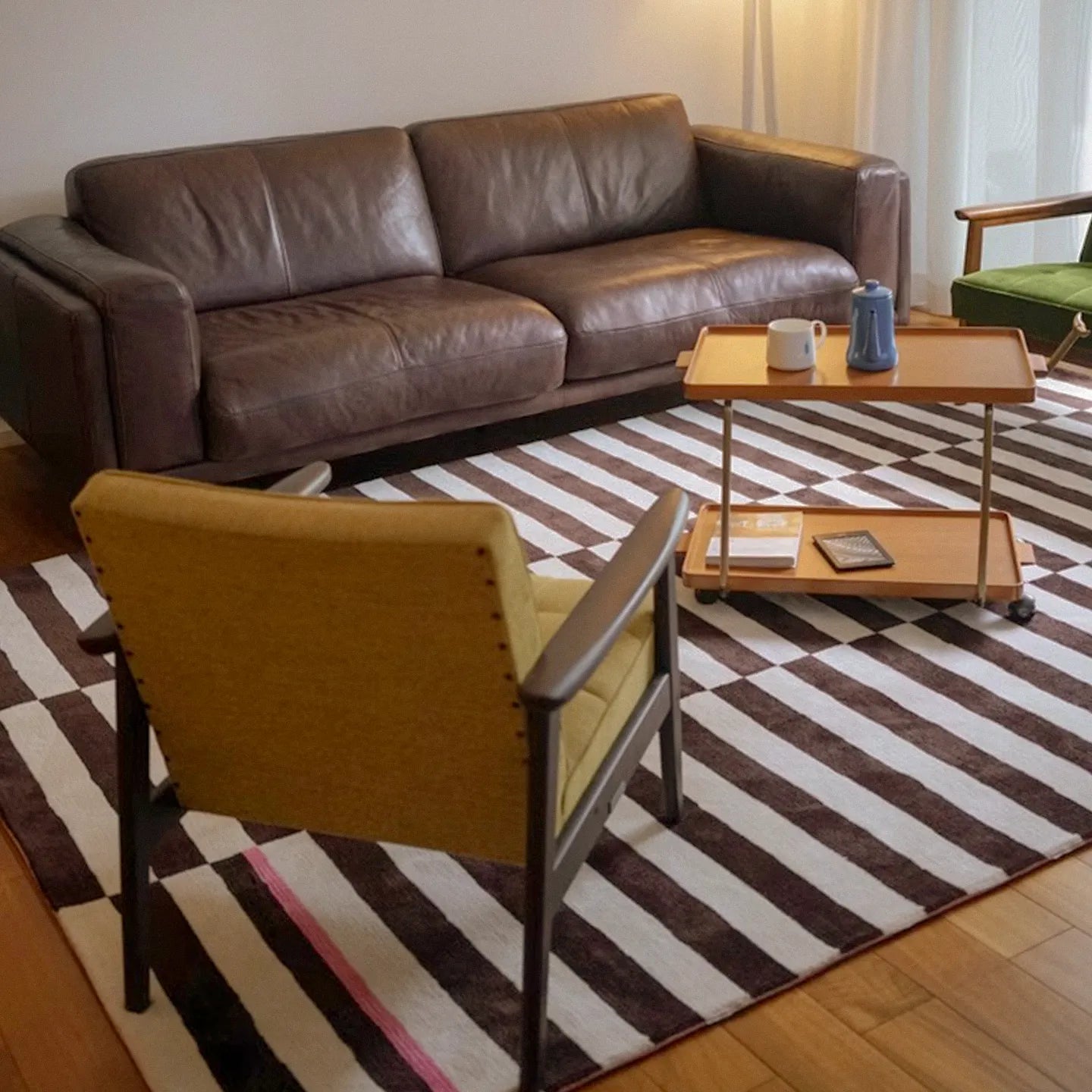 Brown leather sofa and yellow armchair on Clara White and Chocolate Brown Modern Offset Stripe Rug by Housenfriends in a living room.