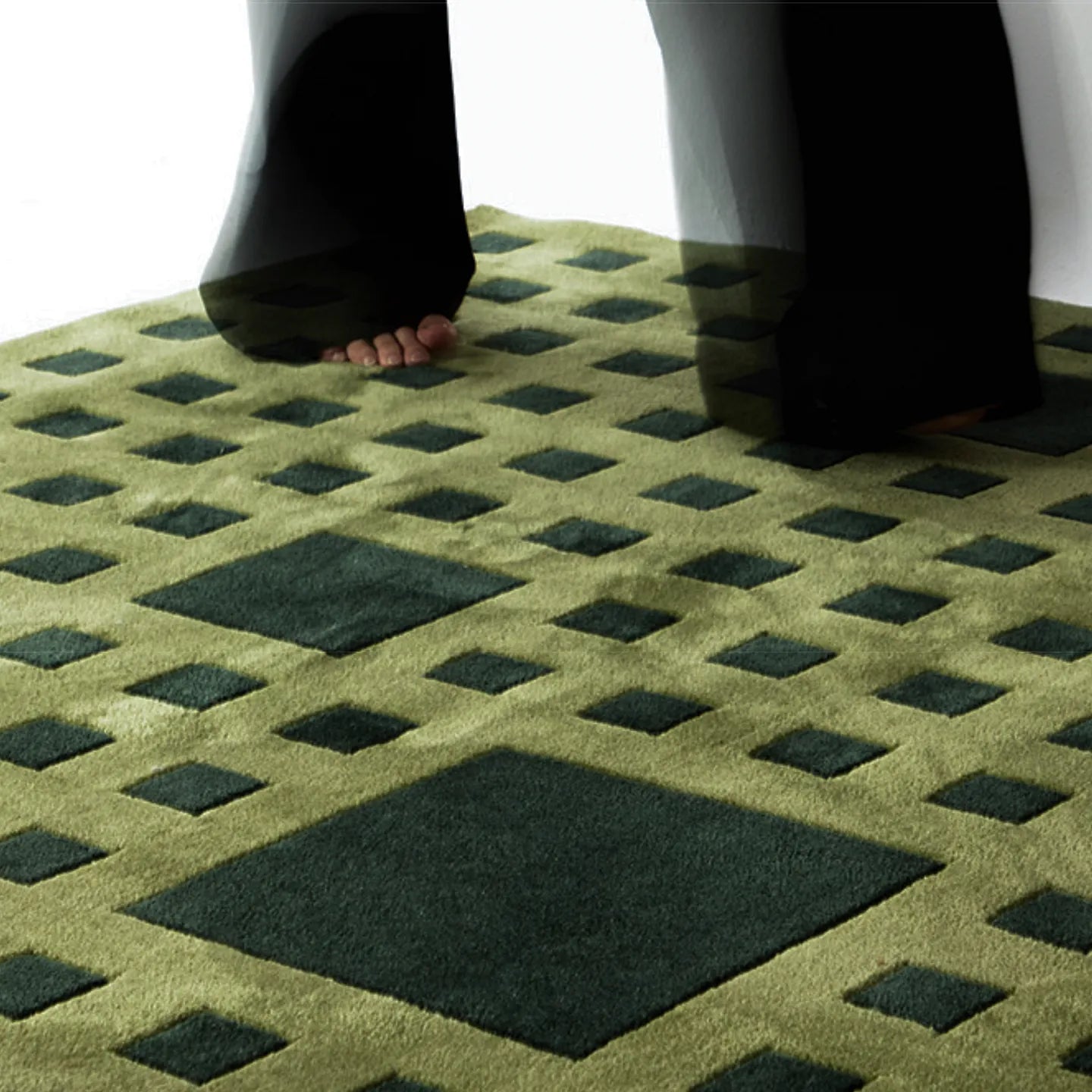 Tessera Olive Green Grid Modern High Low Rug by Housenfriends with feet stepping on it, showing texture and detail.