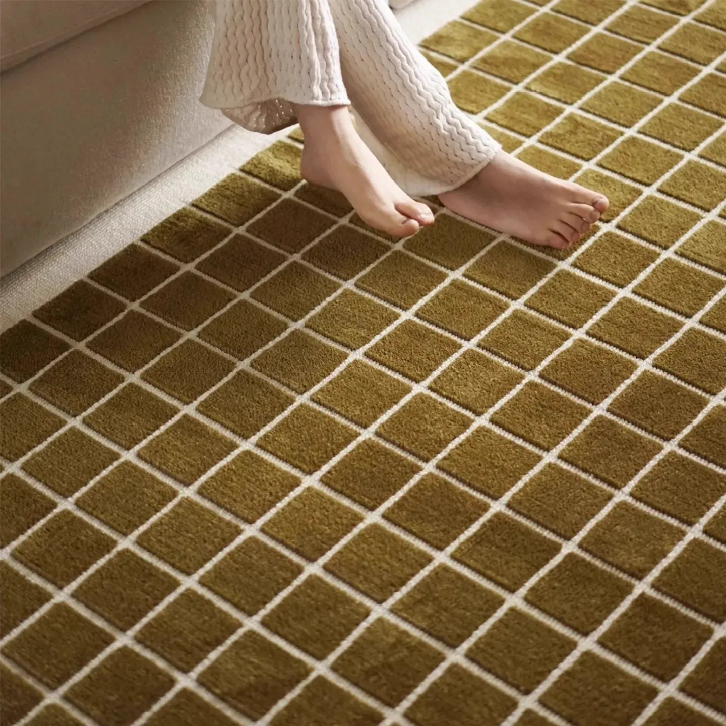Close-up of a person's feet on a textured olive green carpet from Housenfriends