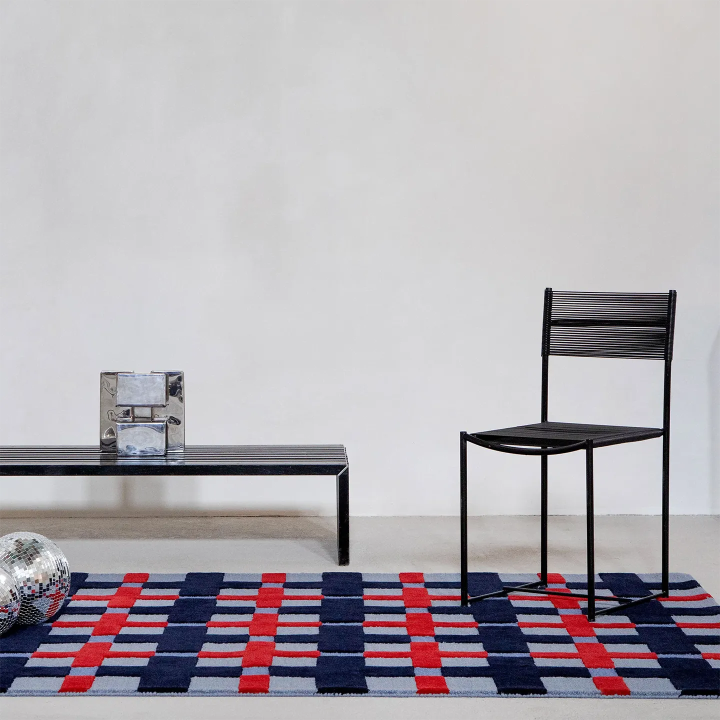Juno navy, red, and dusty blue checkered tufted rug by Housenfriends with black chair and bench