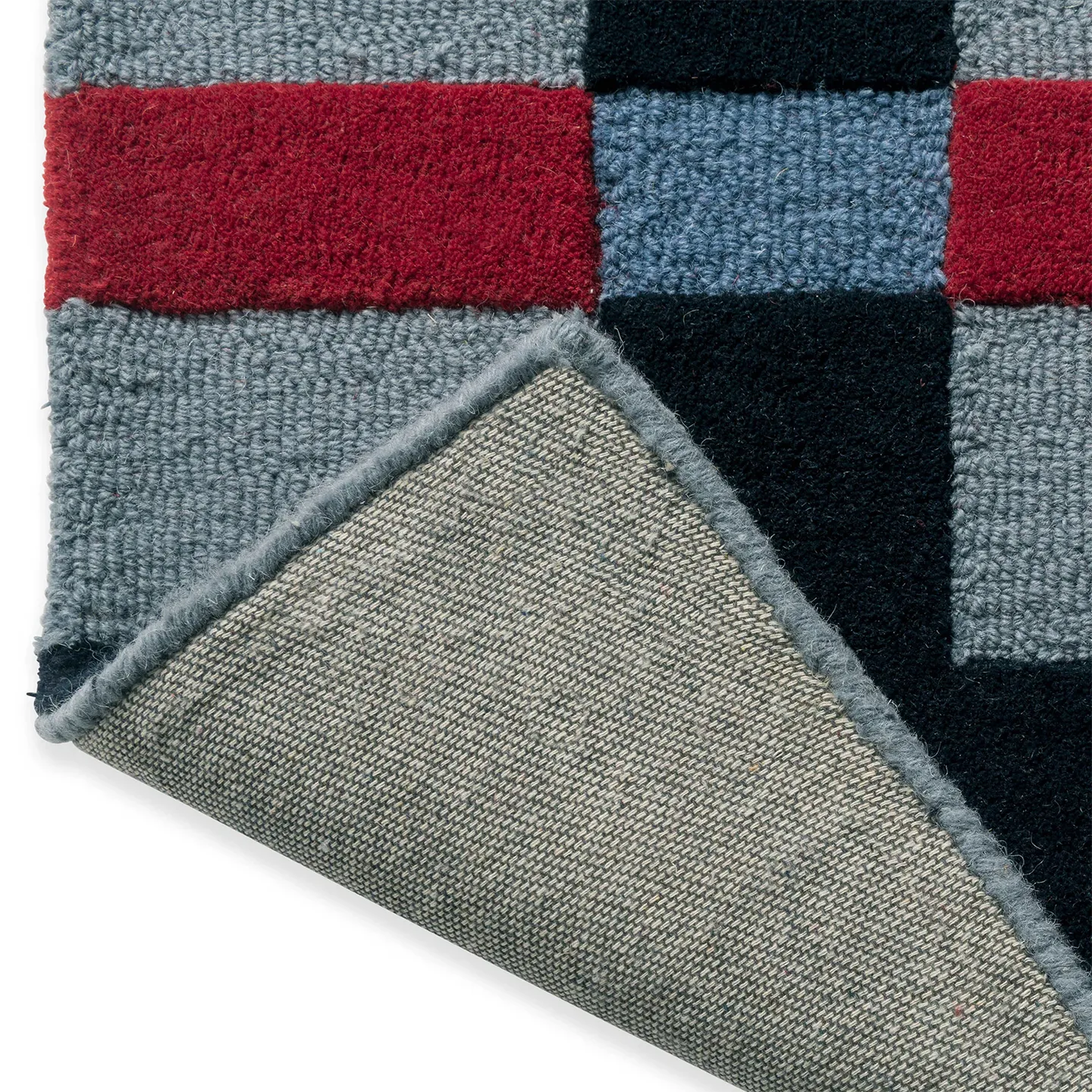 Close-up of the backing of the Juno navy, red, and dusty blue checkered tufted rug by Housenfriends