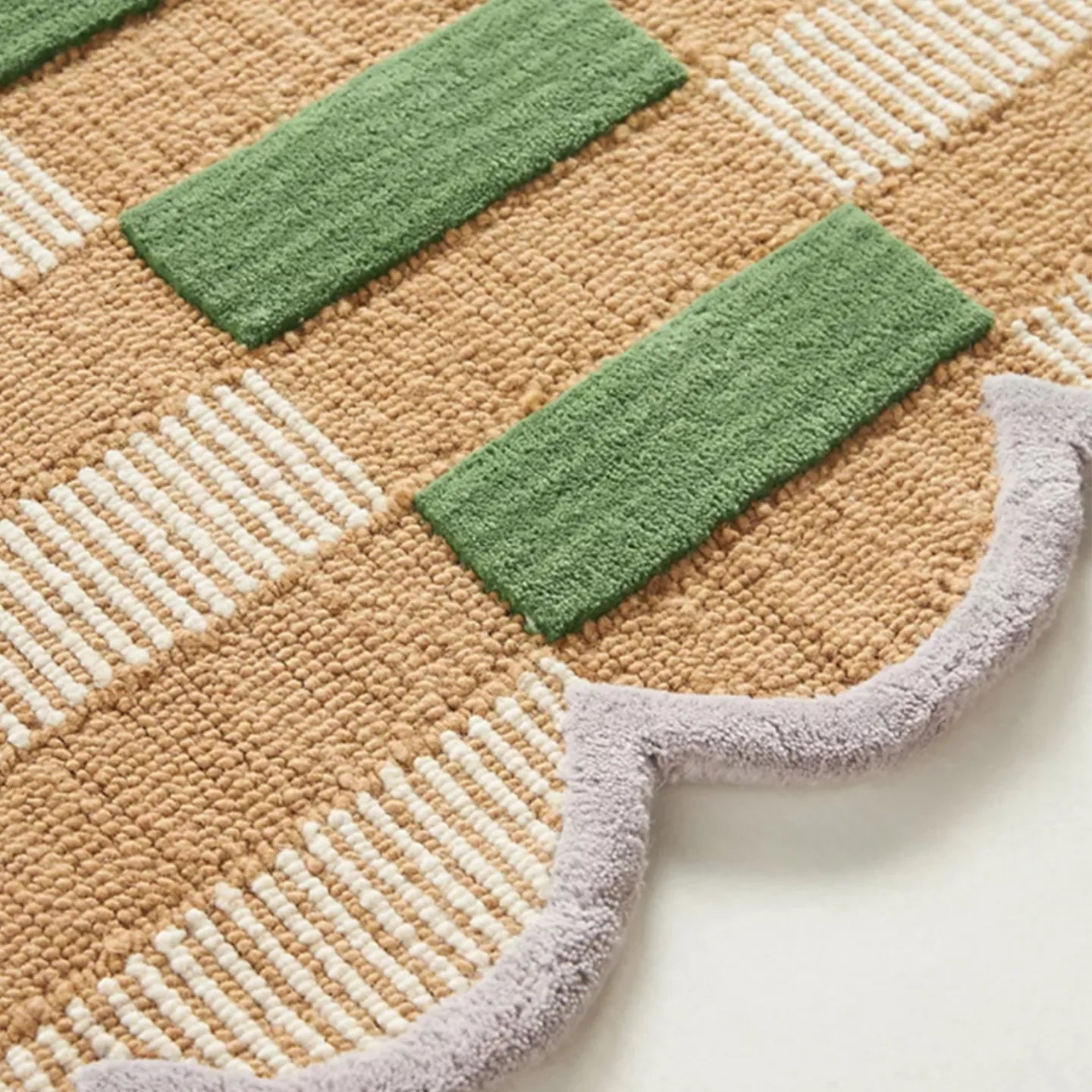 Close-up of pastel green and orange high-low checkered wavy rug by Housenfriends with soft gray border