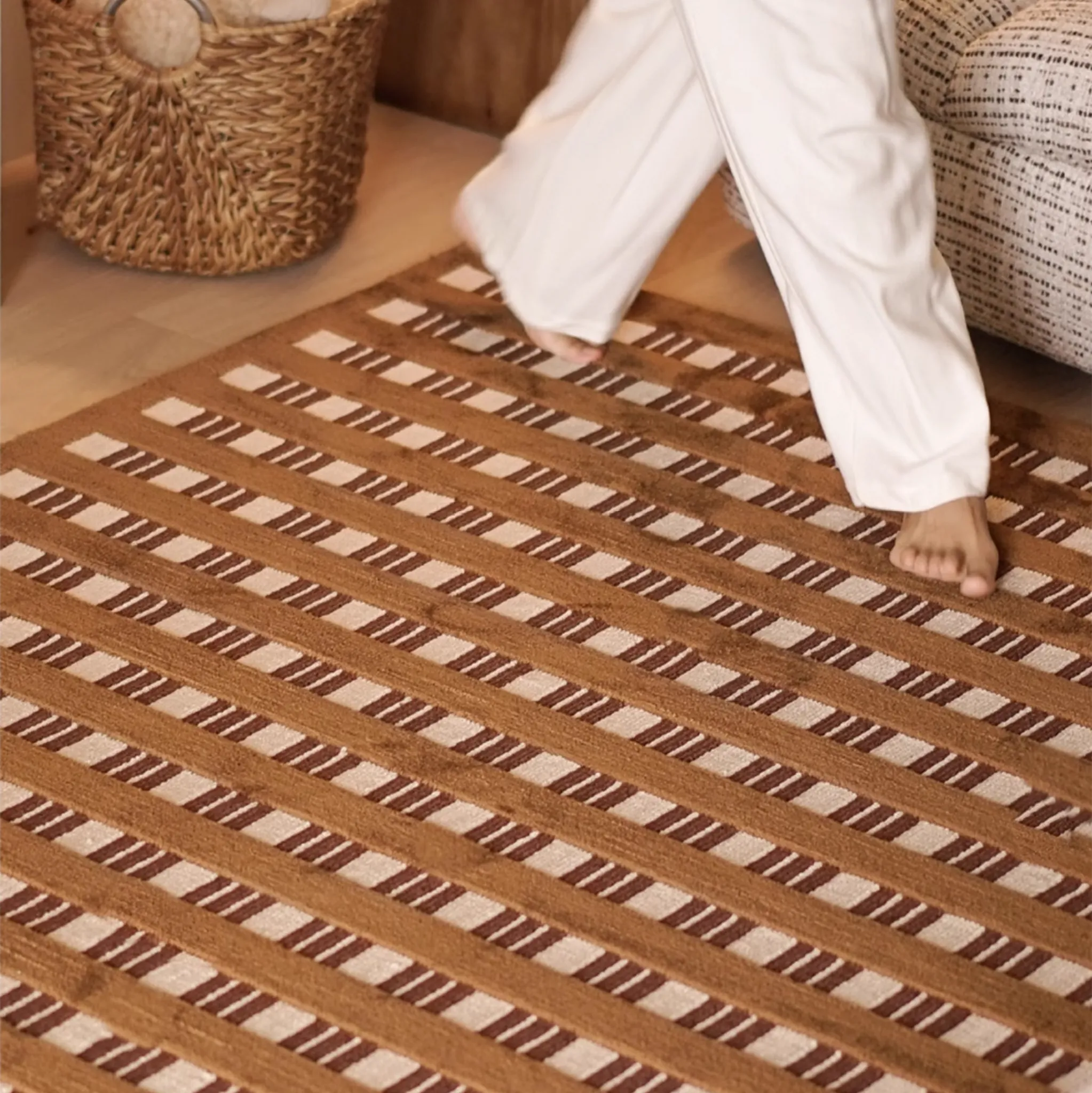 Person walking on Amber Brown and Cream Checkered Textured Rug with a woven basket and sofa