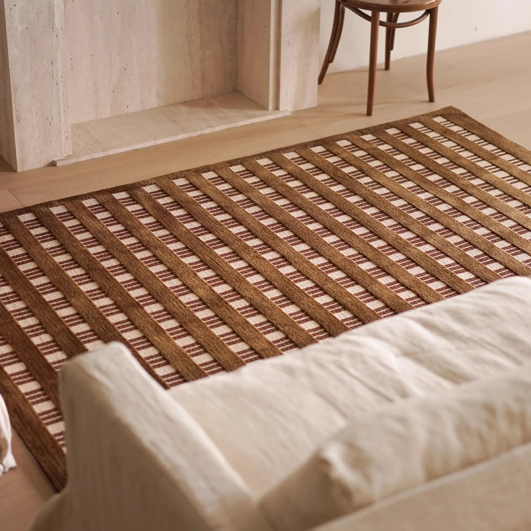 Amber Brown and Cream Checkered Textured Rug a wooden floor with a white sofa in the foreground