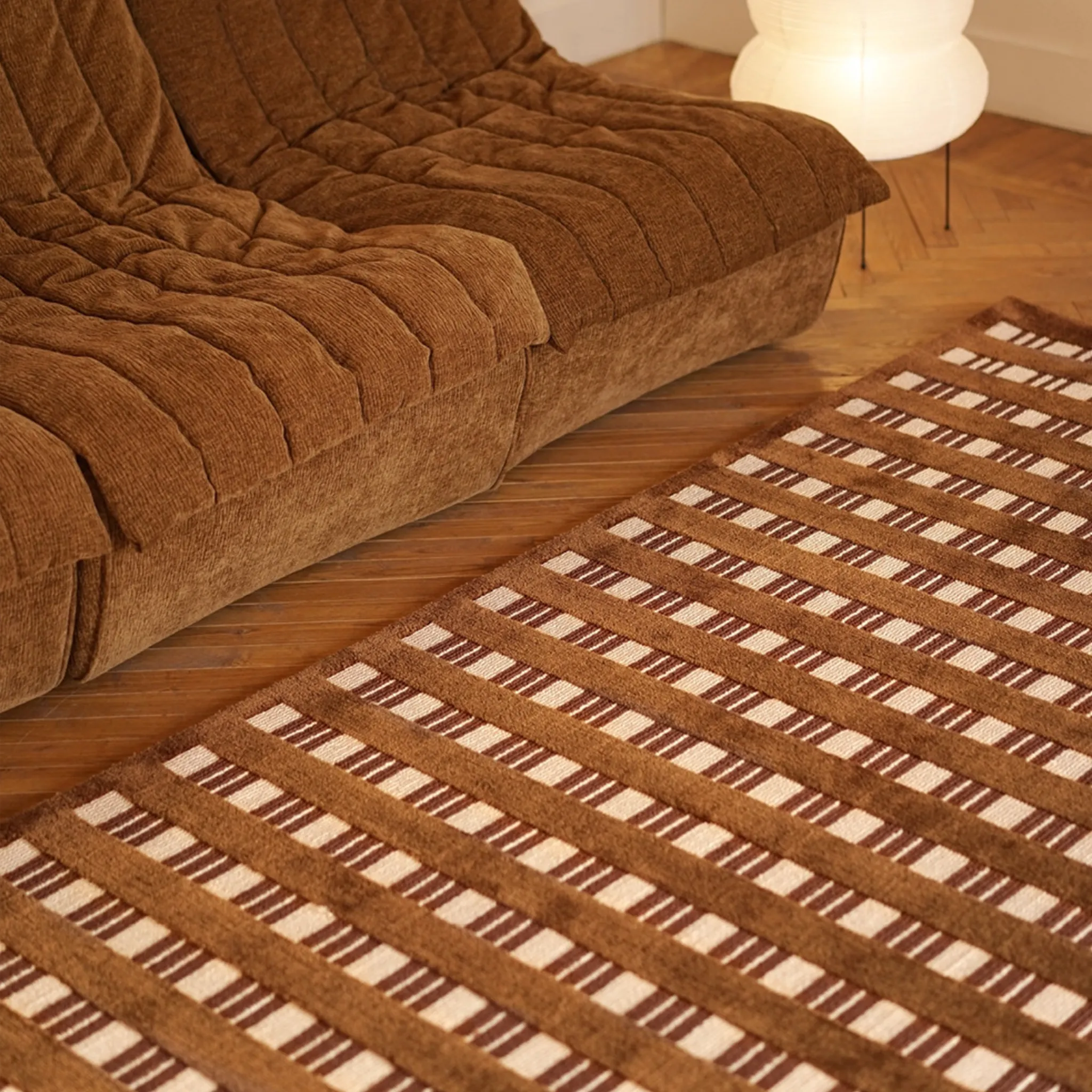 Brown textured sofa and Amber Brown and Cream Checkered Textured Rug on a wooden floor