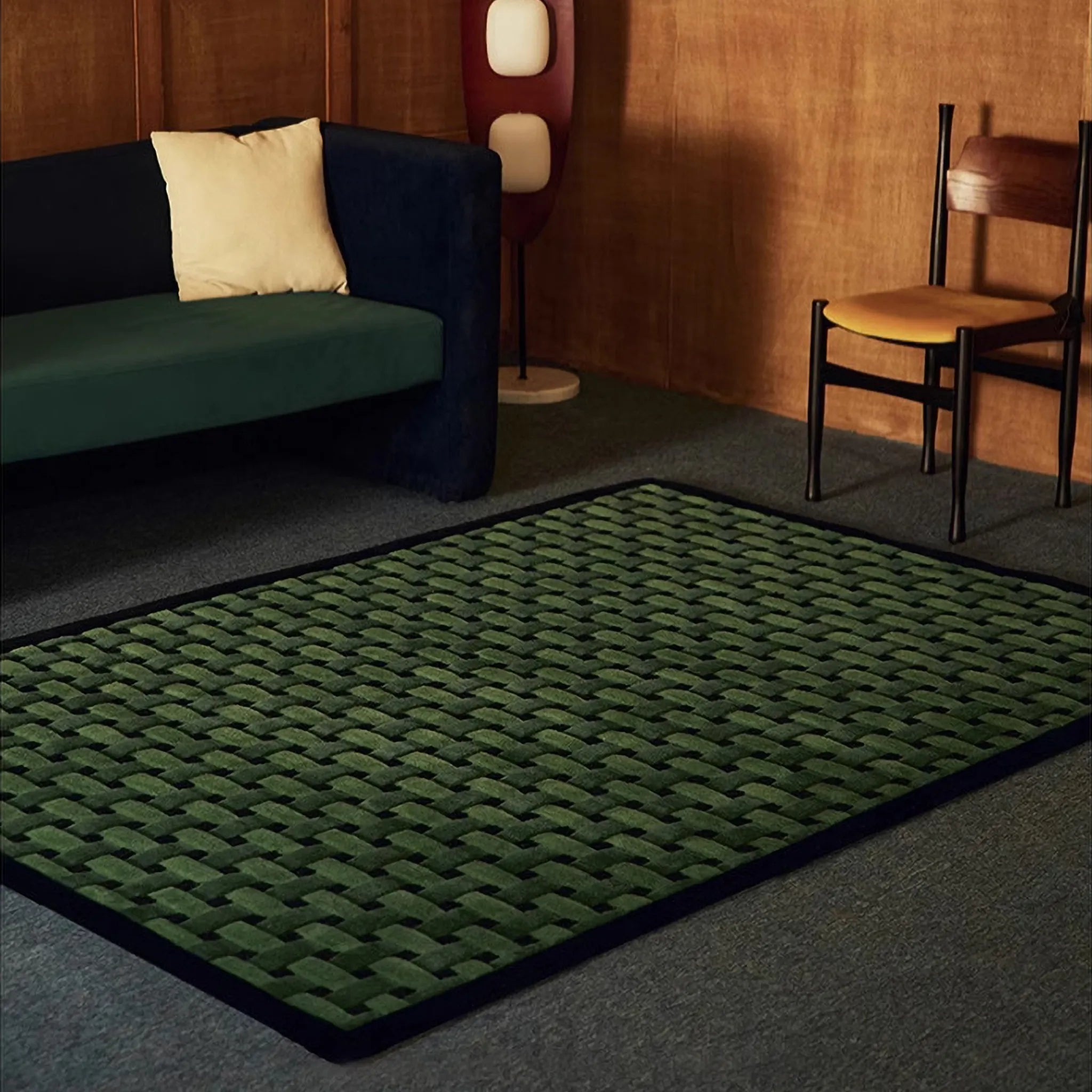 Bambusa Green Woven Grid High Low Tufted Wool Rug by Housenfriends on floor with a green sofa and wooden wall.