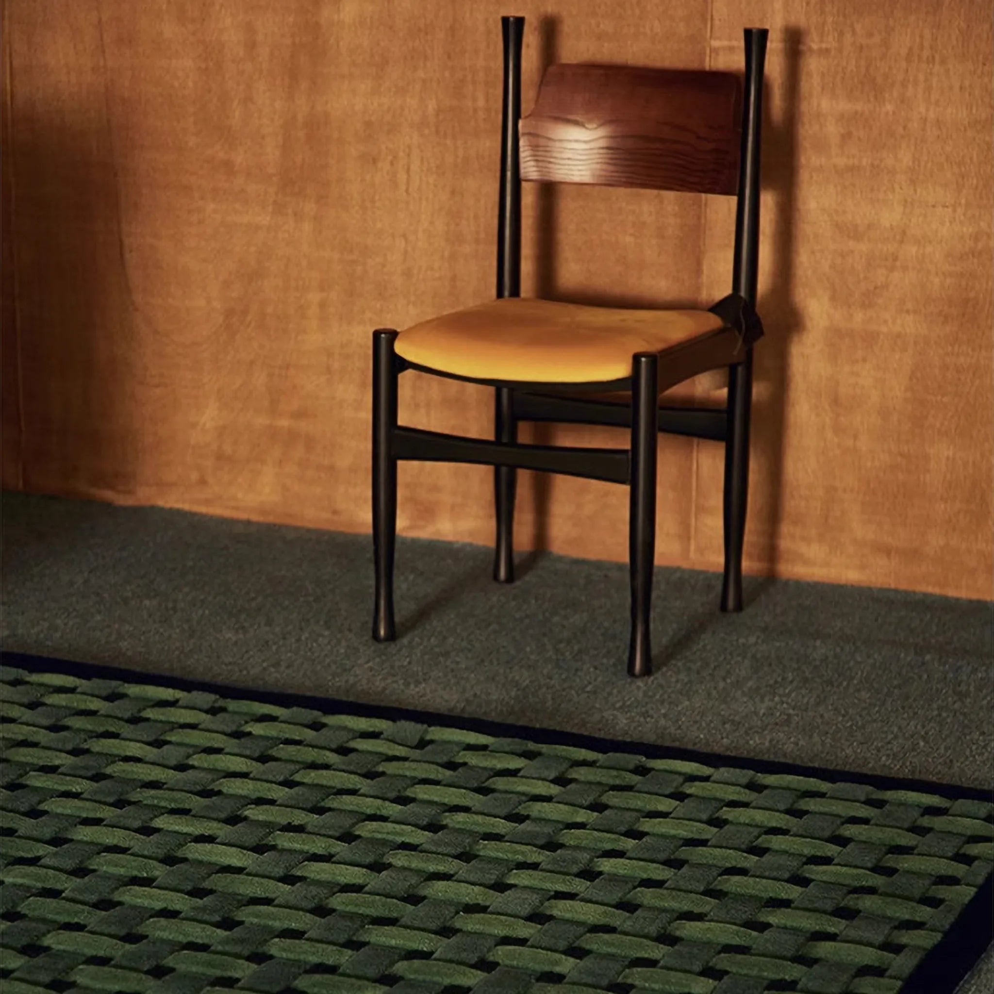 Wooden chair with cushion on Bambusa Green Woven Grid High Low Tufted Wool Rug by Housenfriends against wall