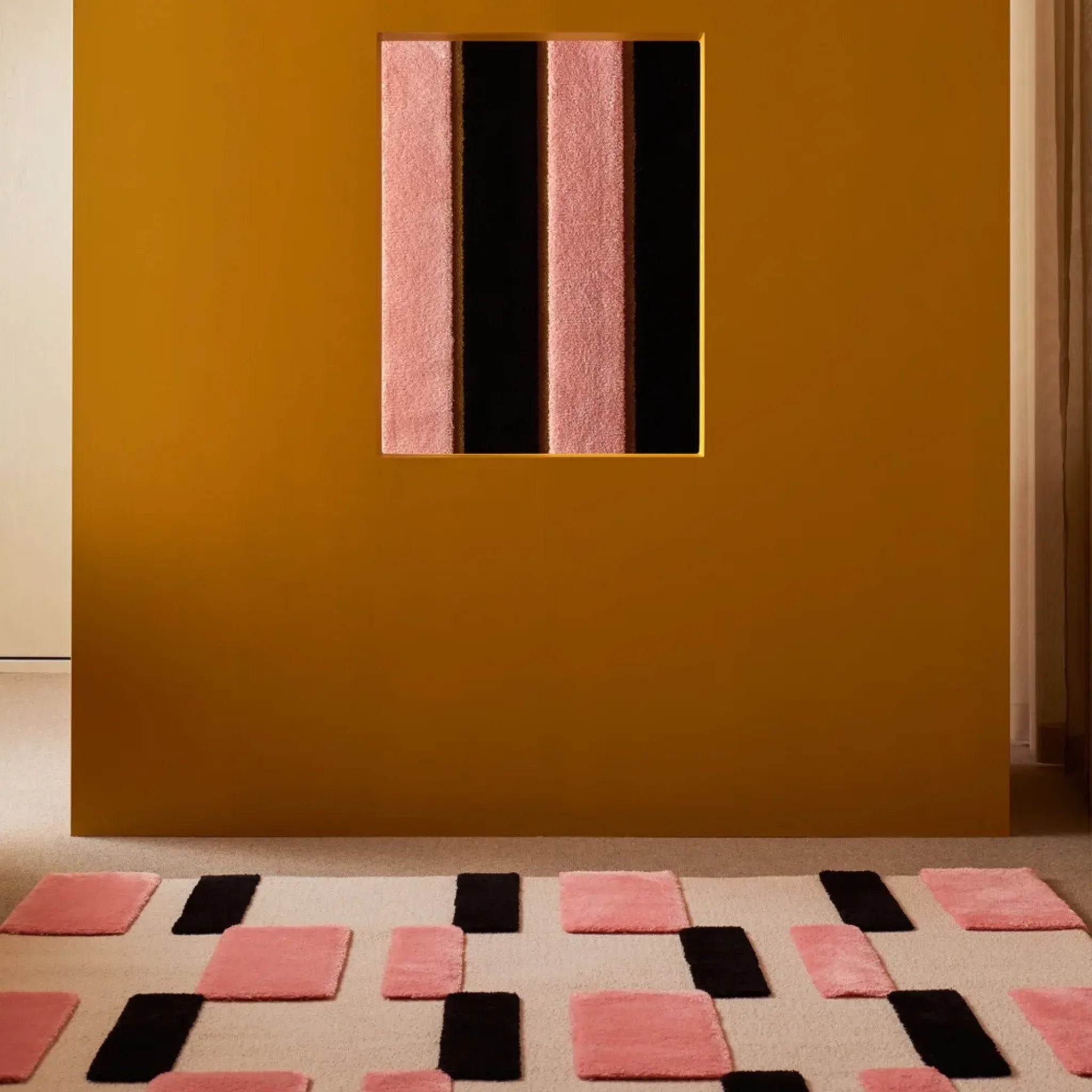 Wall with geometric pink and black design and a Blush Pink Black Ivory Checkered High Low Rug on floor.