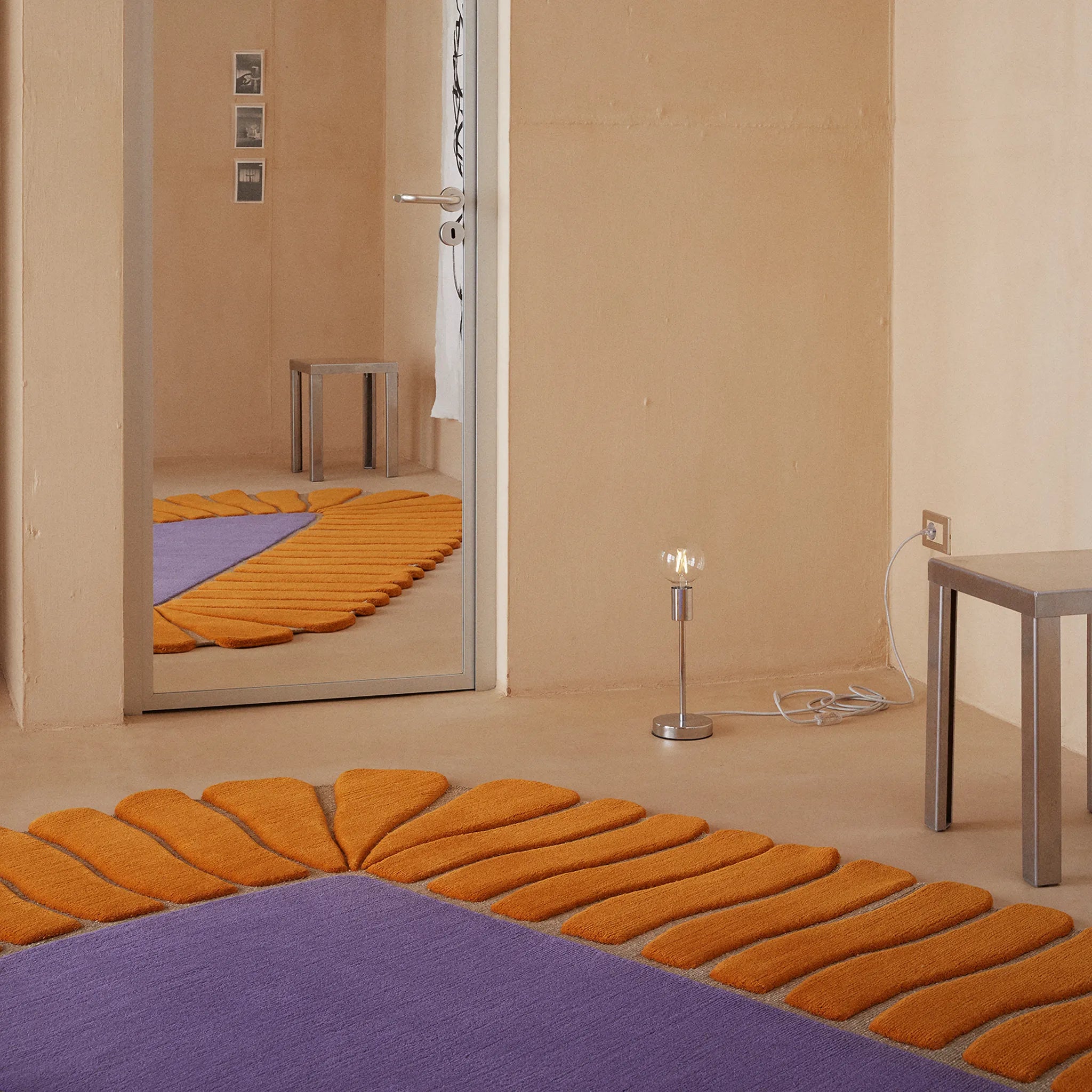 Coquille Purple Orange Seashell Shaped Sculpted Rug by Housenfriends in front of a mirror with a beige wall.