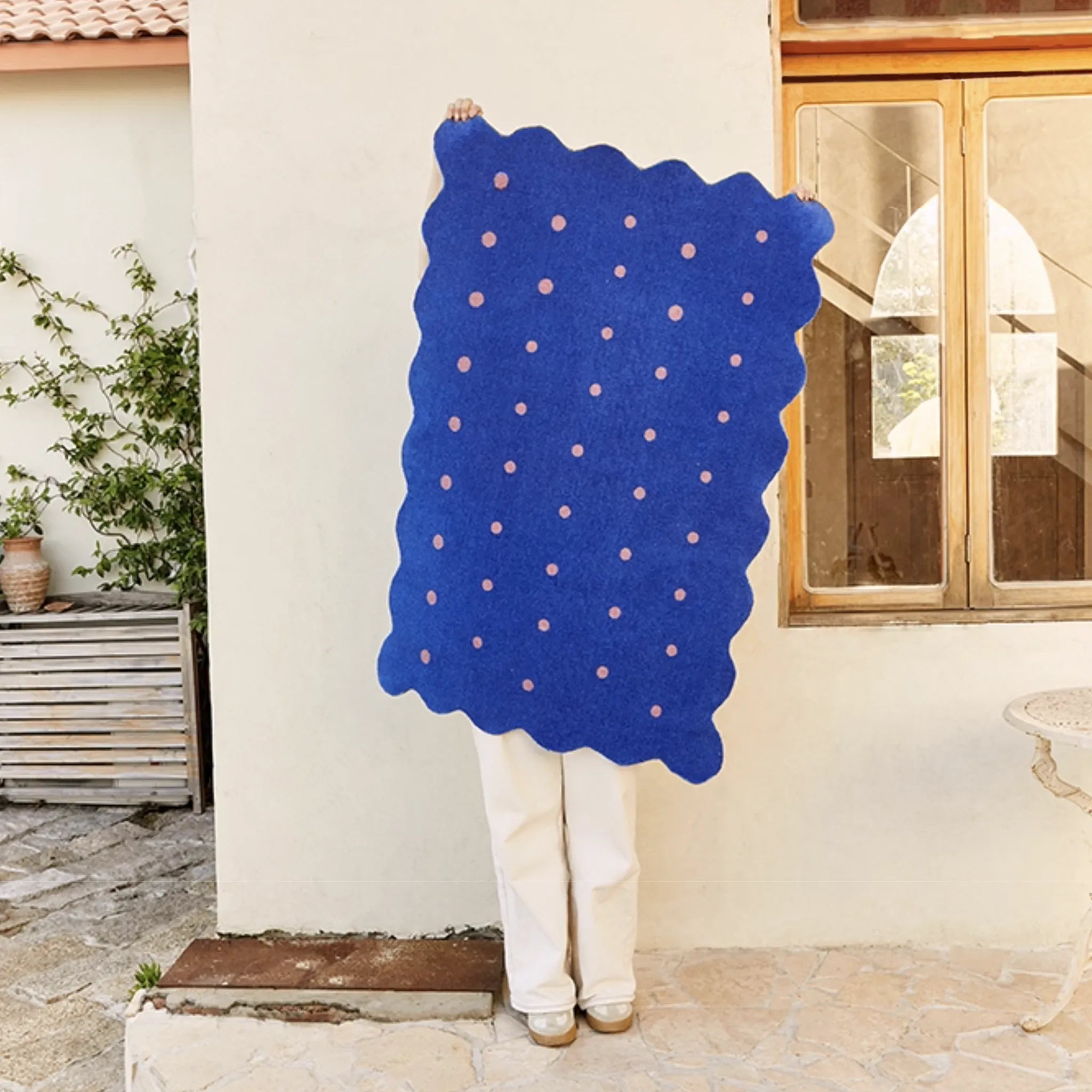Person holding Arden Klein Blue & Pink Polka Dots Scalloped Rug by Housenfriends against a white wall.