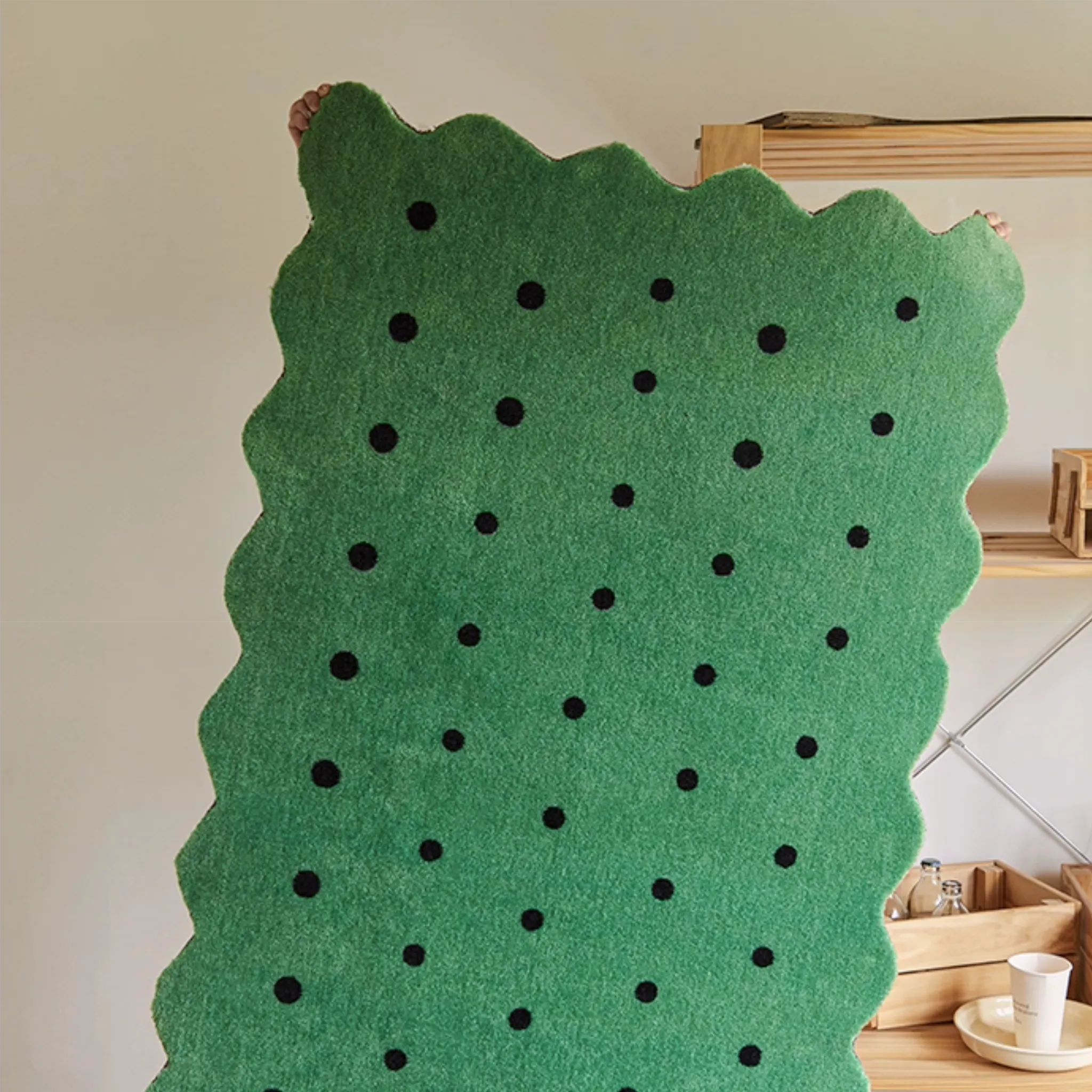 Arden Green & Black Polka Dots Scalloped Rug by Housenfriends held against a neutral wall.