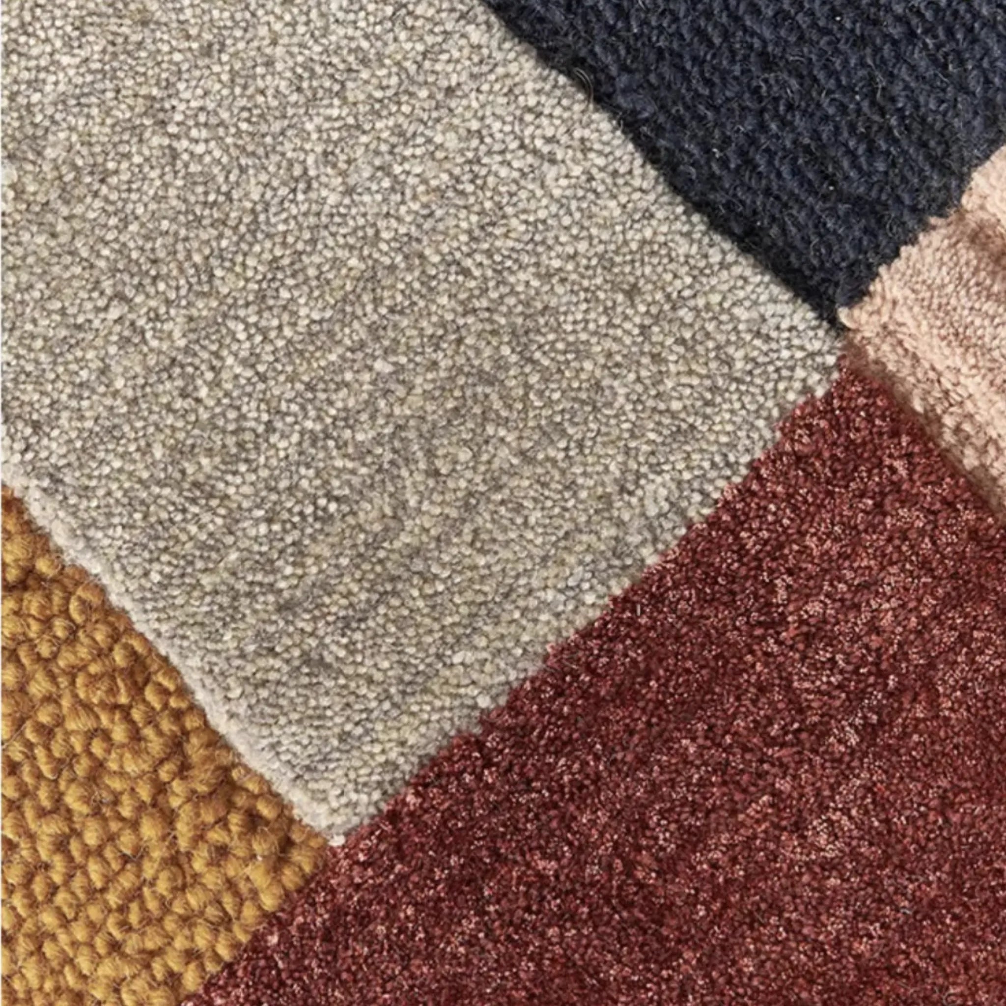 Close-up of a textured rug with geometric pattern in Rust, Mustard, Navy, Pink, and Grey