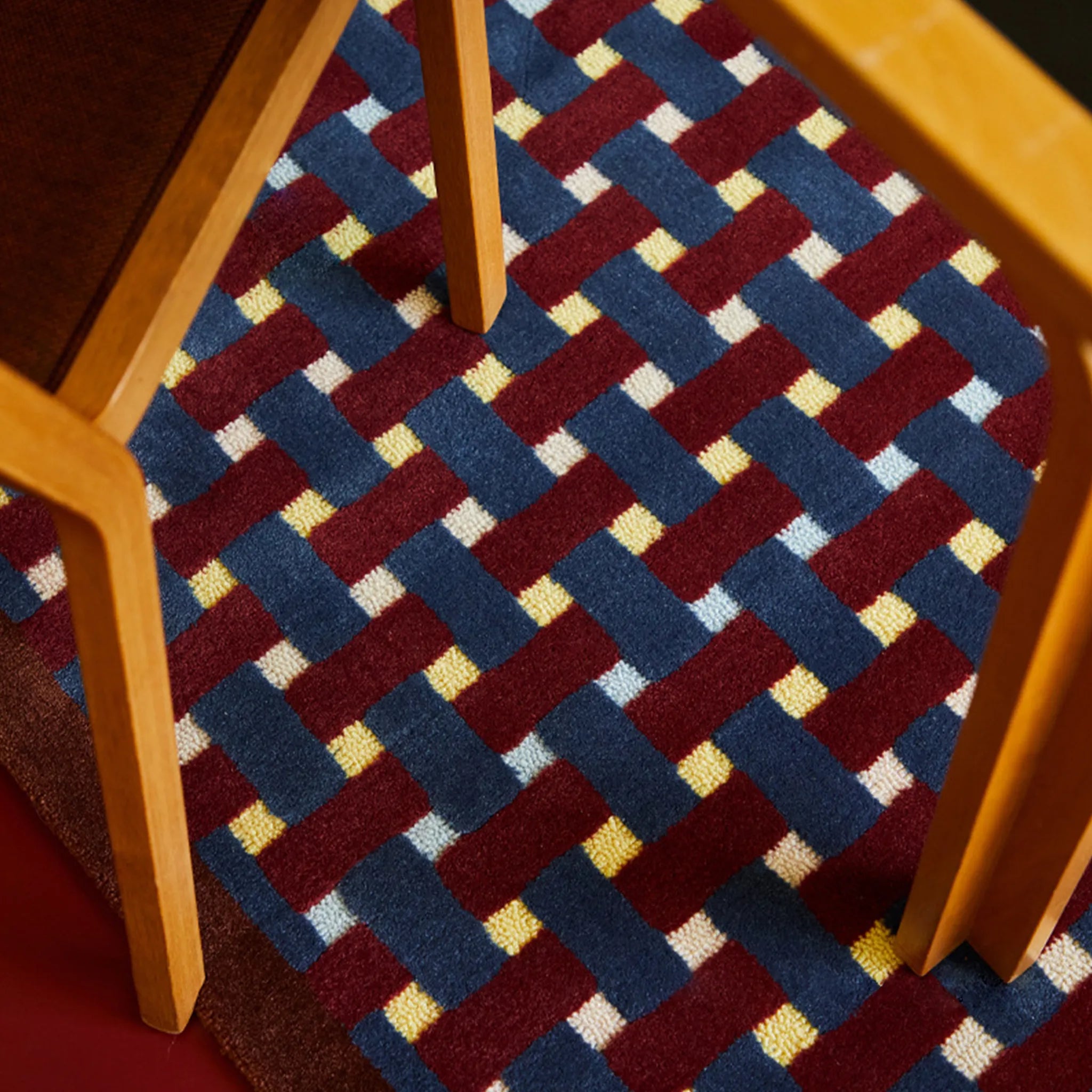 Close-up of a Mondrian Red Navy Beige Retro Checkered Wool Rug with wooden frame