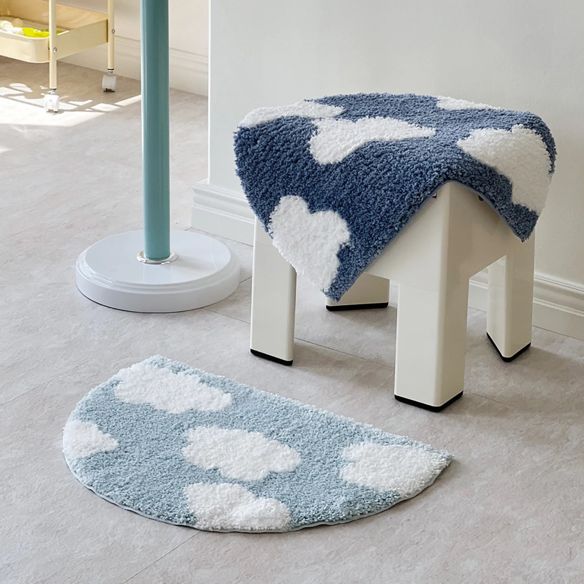 White stool with blue cloud-patterned cover next to a matching cloud-patterned rug on a light grey floor.