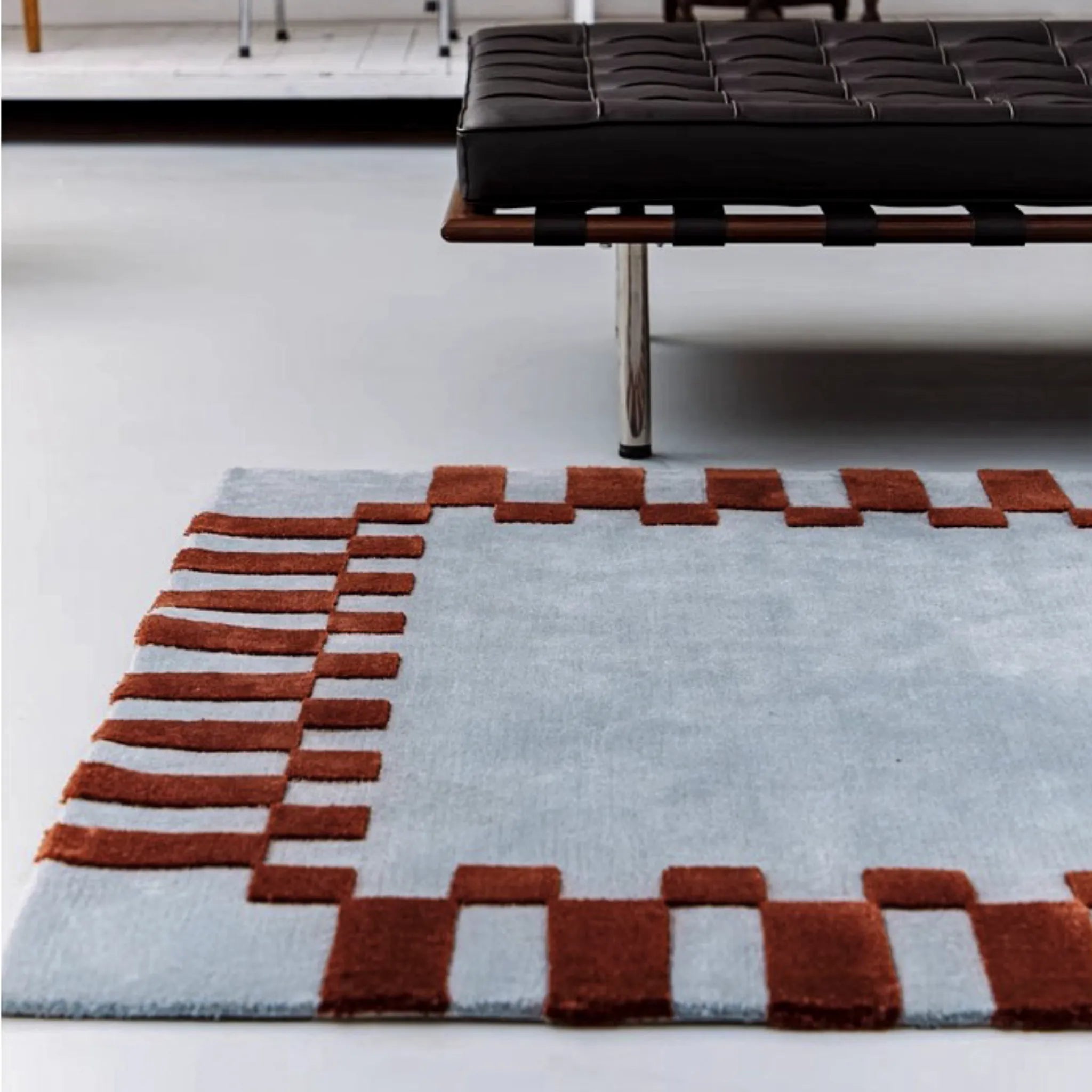 Acropolis Slate Blue and Red High Low Wool Rug by Housenfriends on floor next to a black bench.