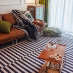 Living room with a brown leather sofa, a wooden coffee table on Stockholm Black and White Modern Offset Stripe Rug by Housenfriends