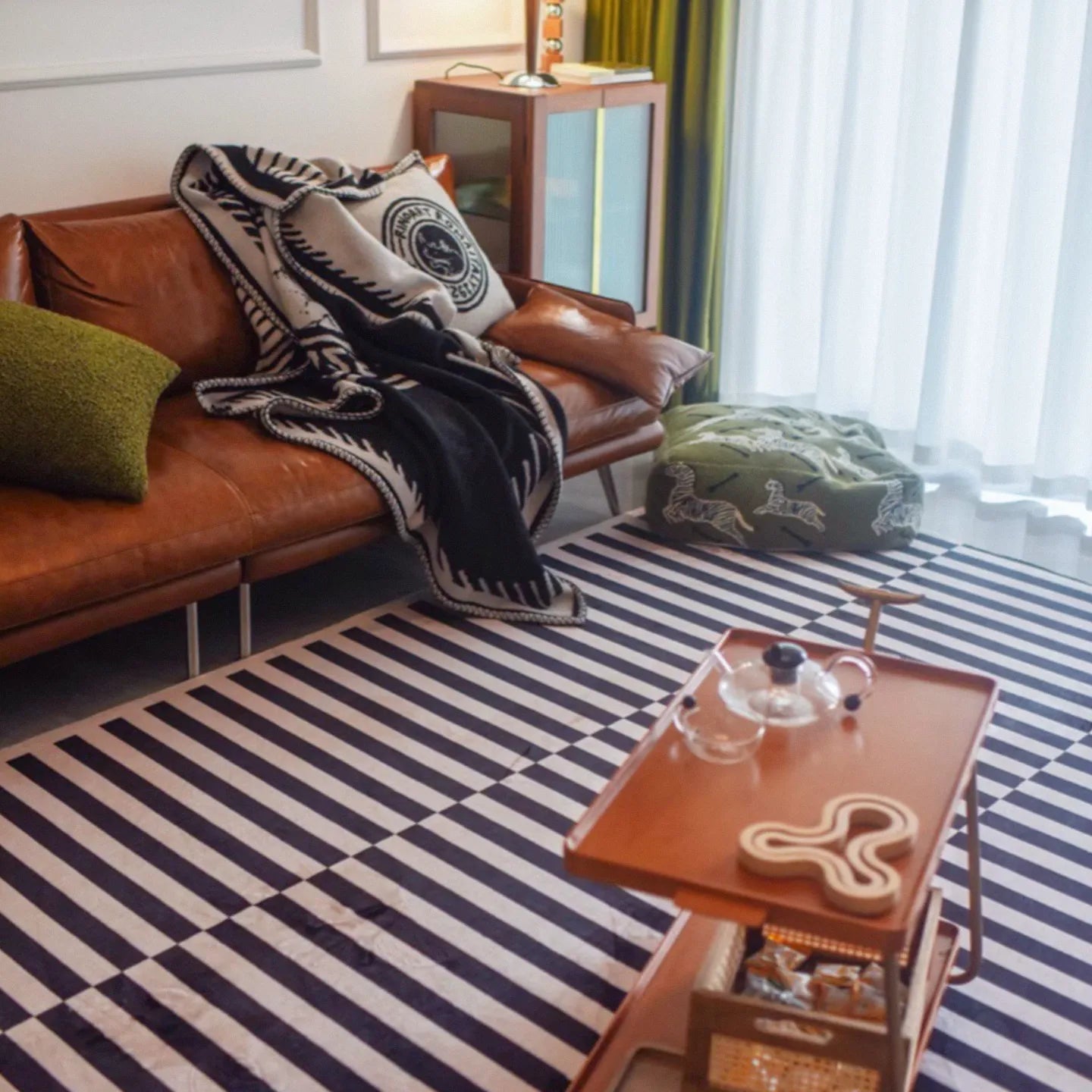 Living room with a brown leather sofa, a wooden coffee table on Stockholm Black and White Modern Offset Stripe Rug by Housenfriends