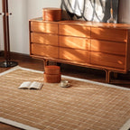 Wooden dresser with decorative items on a white rug featuring a caramel gold grid pattern by Housenfriends
