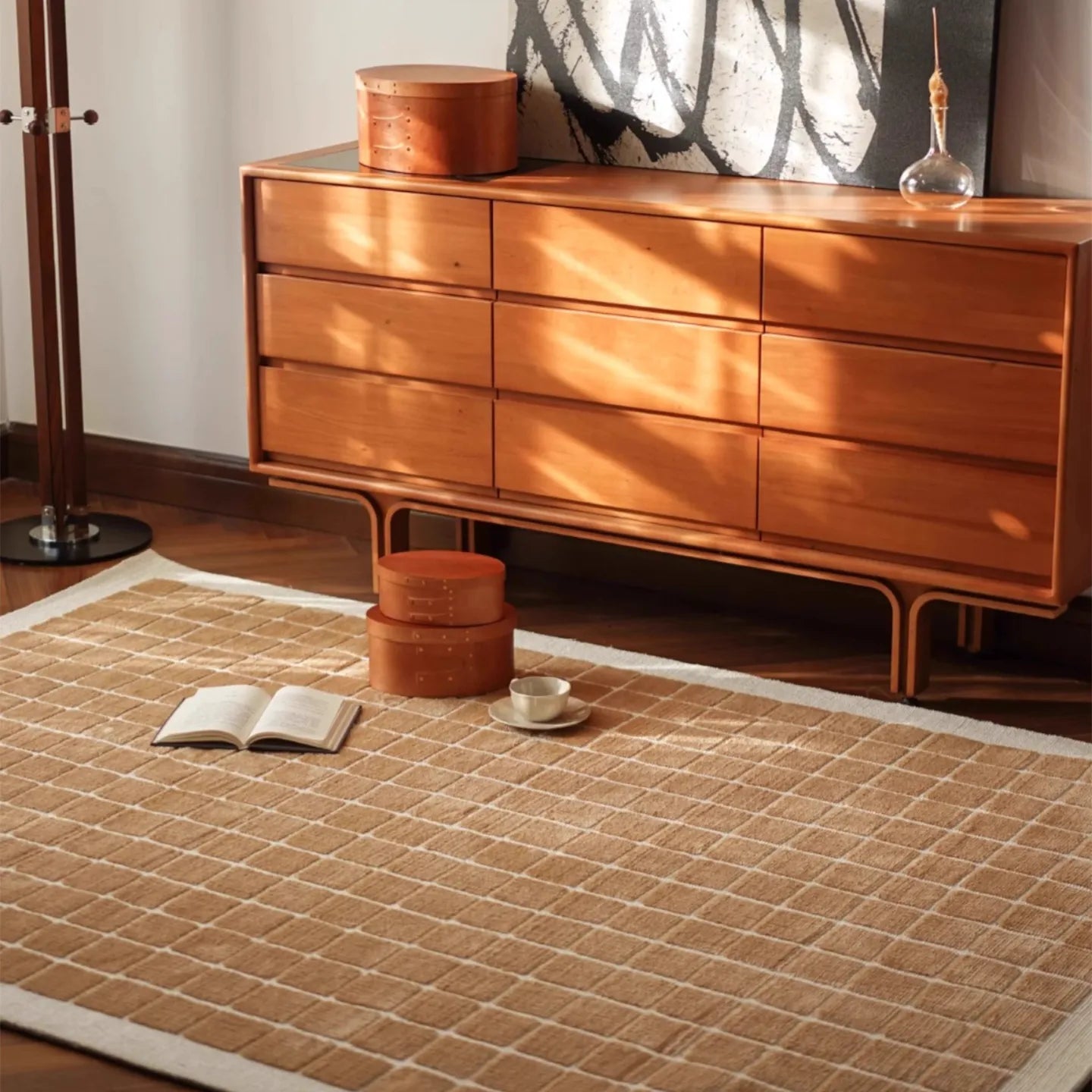 Wooden dresser with decorative items on a white rug featuring a caramel gold grid pattern by Housenfriends