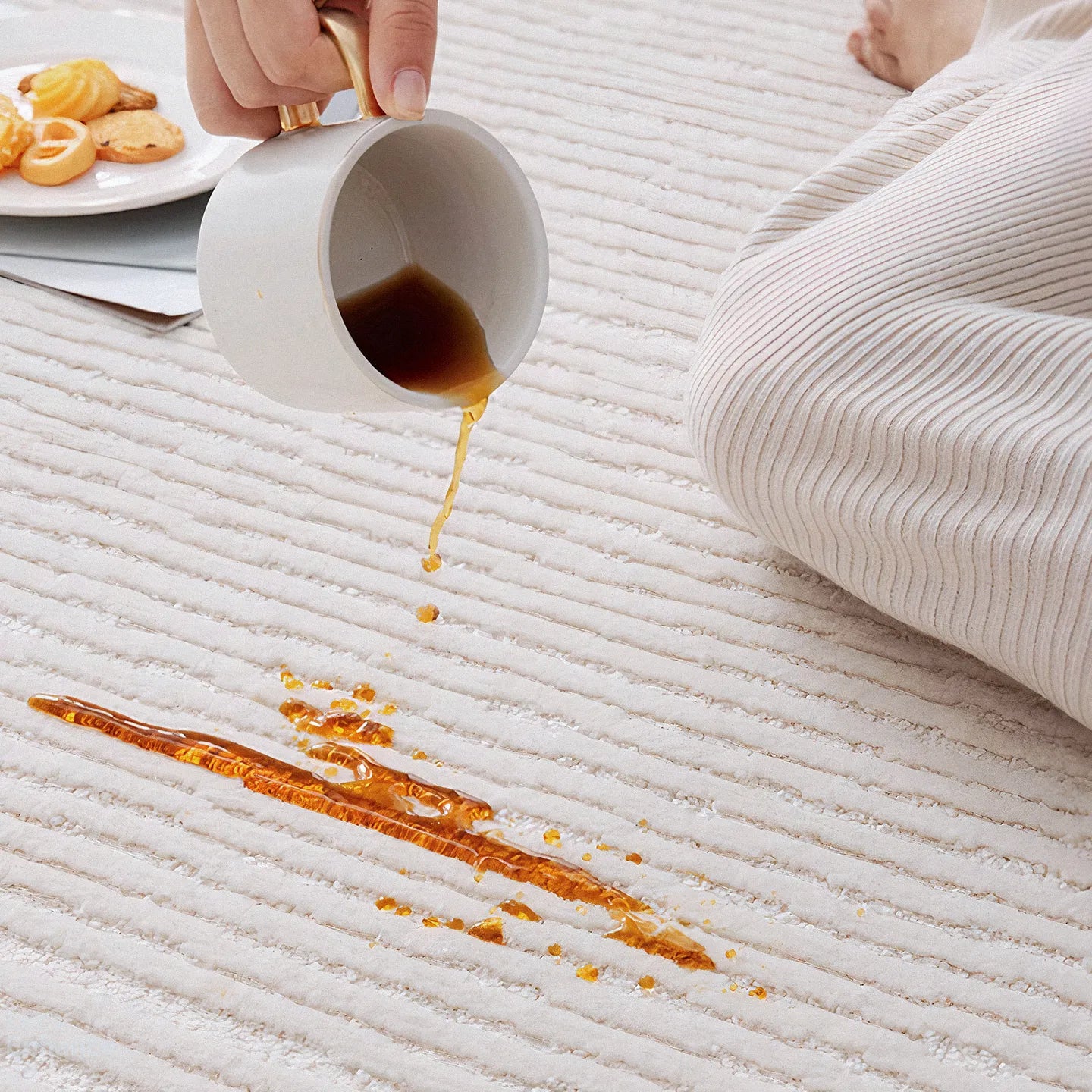Close-up of coffee spilling on Rae off-white modern rug by Housenfriends, with water-resistant, easy-to-clean surface.