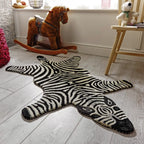 Zibi small zebra animal shaped rug in black and white by Housenfriends on a wooden floor with toys