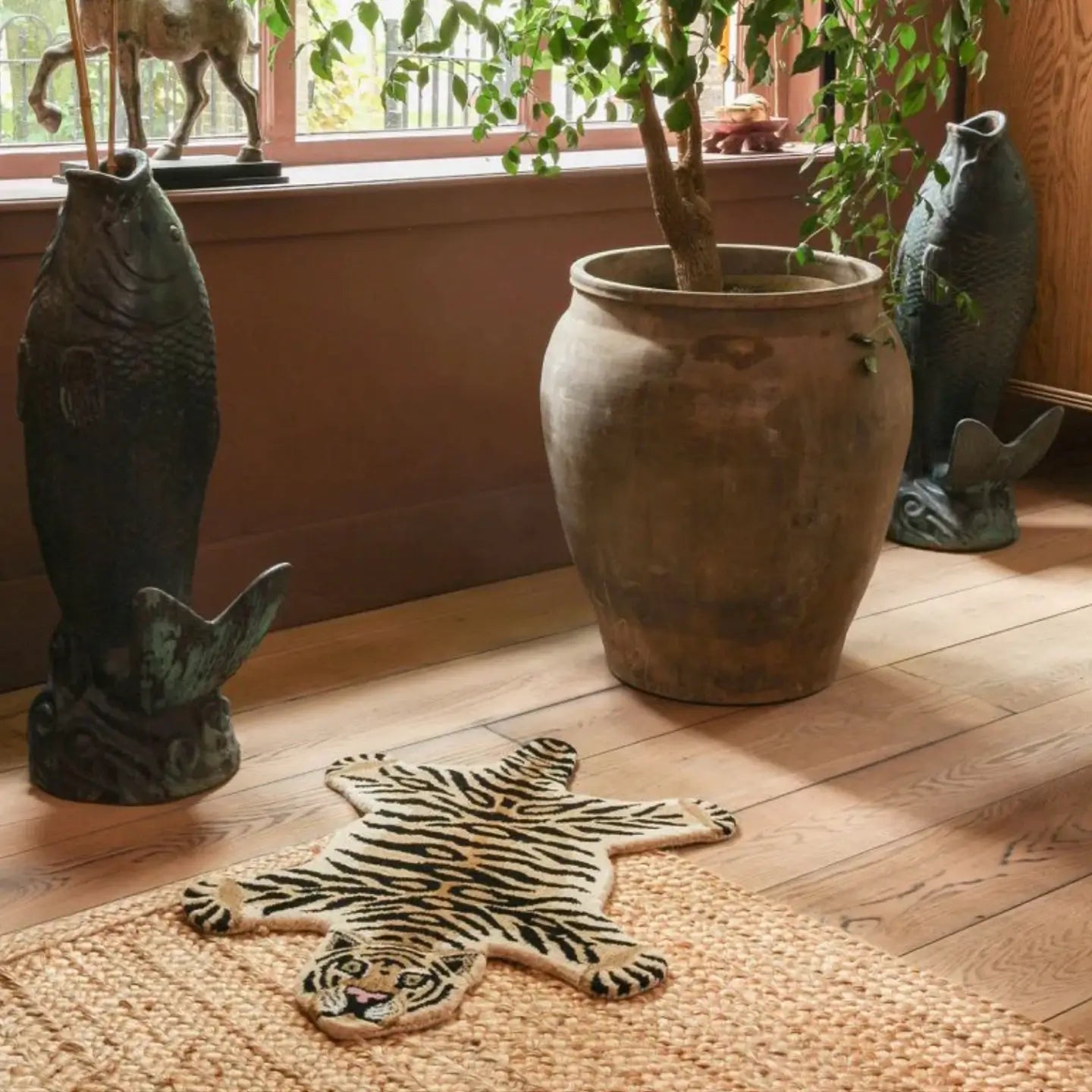 Room interior with a tiger-patterned wool rug by Housenfriends, potted plant, and fish decorations on a wooden floor.