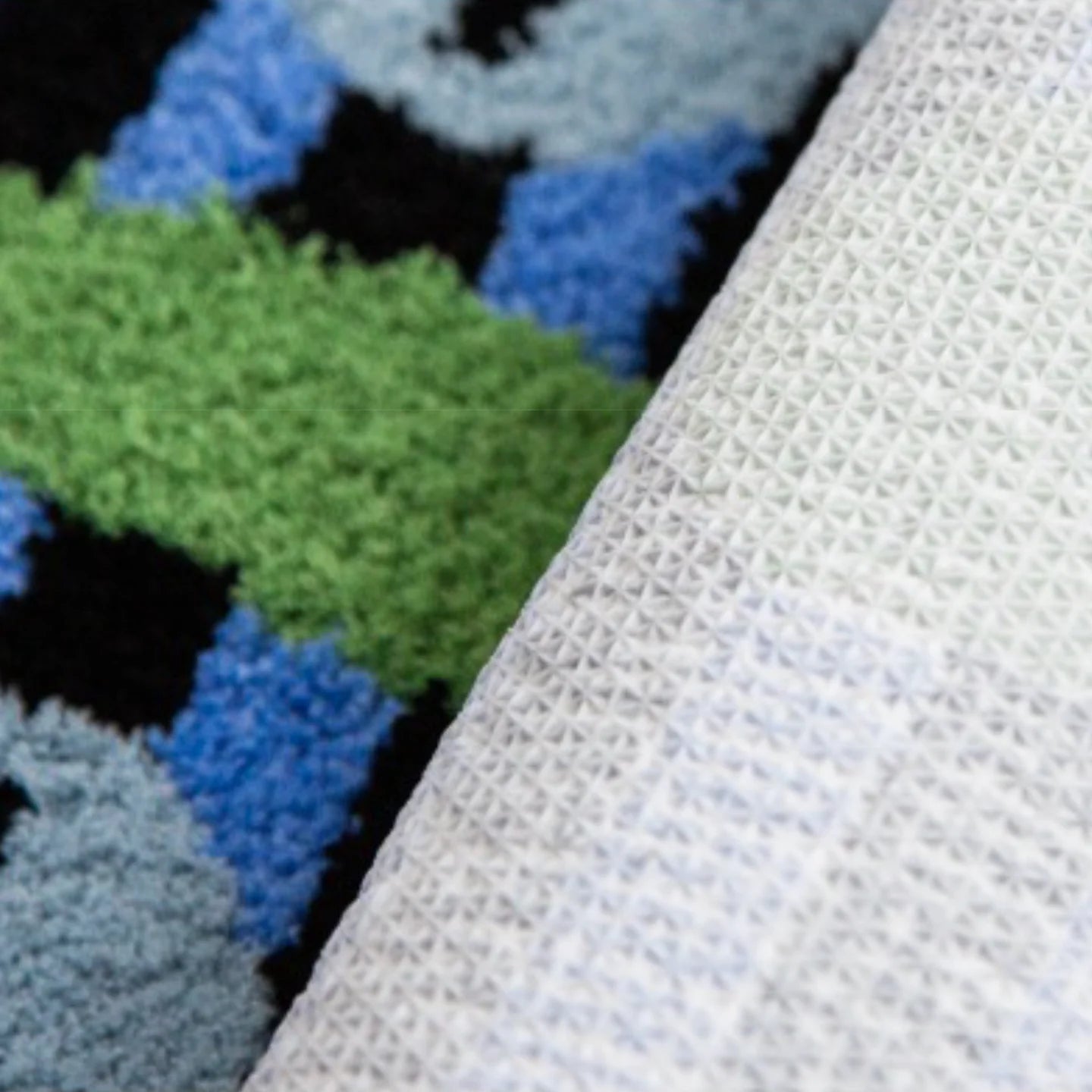 Close-up of Milo green small oval shaggy African mask rug by Housenfriends, showing non-slip backing