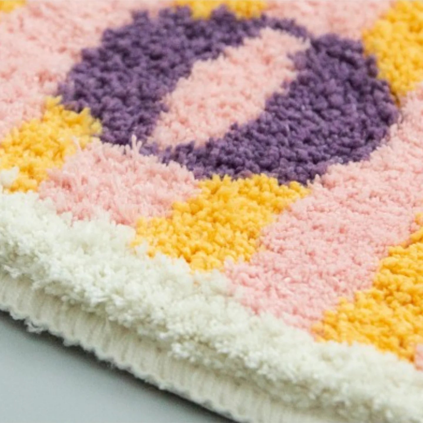 Close-up of Milo pink small African mask rug by Housenfriends, hand-tufted with pink, purple, and yellow stripes