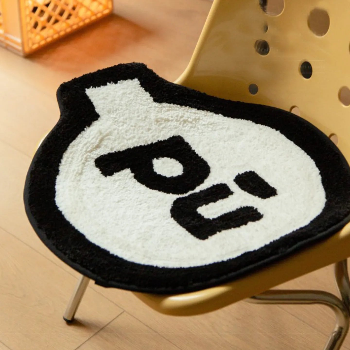 Pu white small shaggy rug with black outline by Housenfriends, grenade-like shape, on a yellow chair