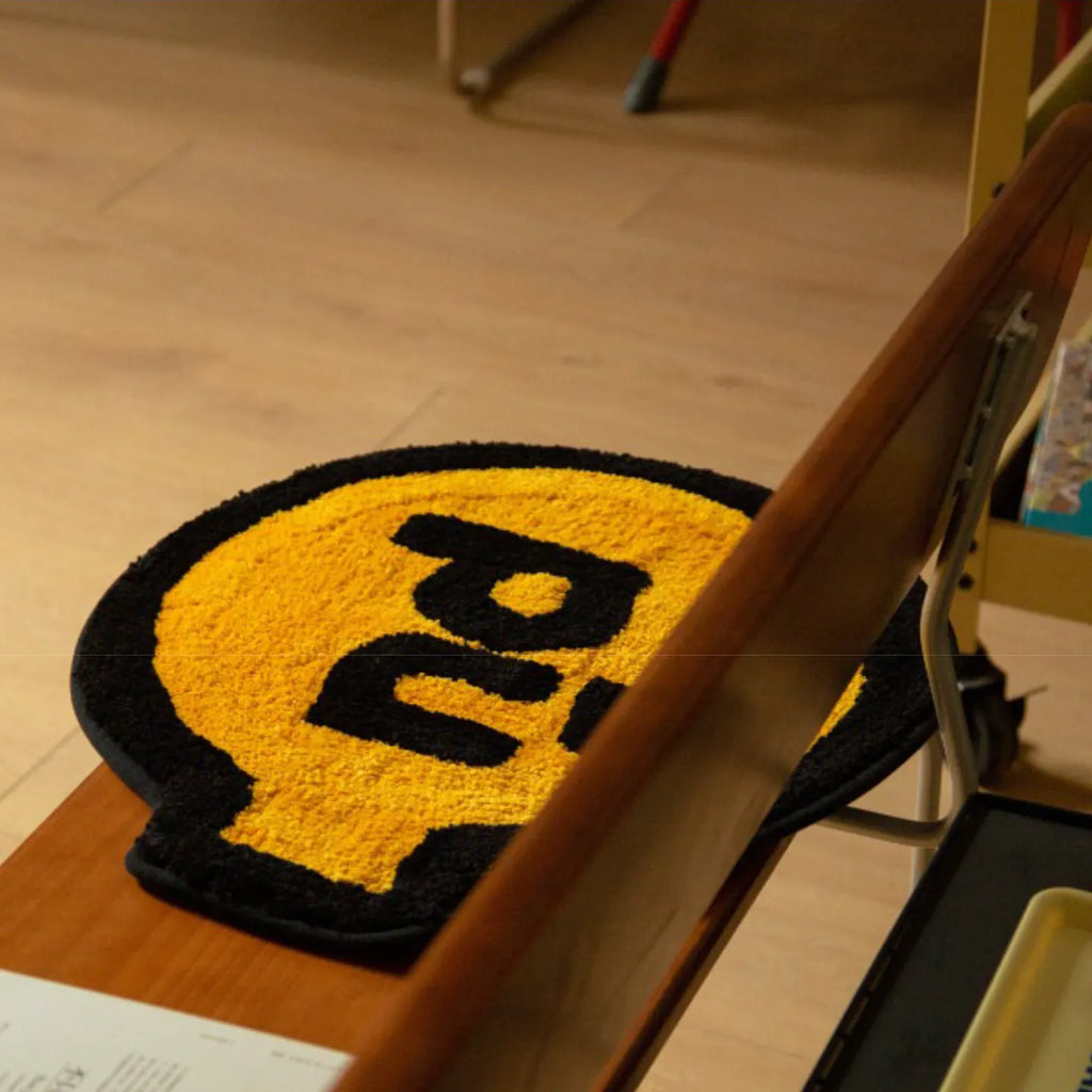 Pu yellow small shaggy rug with black outline by Housenfriends, grenade-like shape, on a wooden chair
