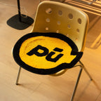 Pu yellow small shaggy rug with black outline by Housenfriends, grenade-like shape, on a yellow chair