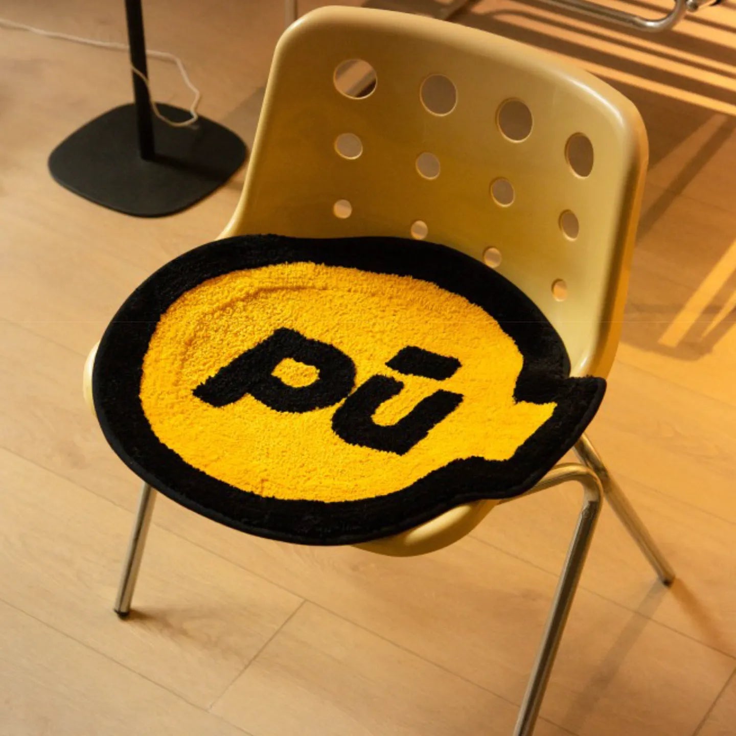 Pu yellow small shaggy rug with black outline by Housenfriends, grenade-like shape, on a yellow chair