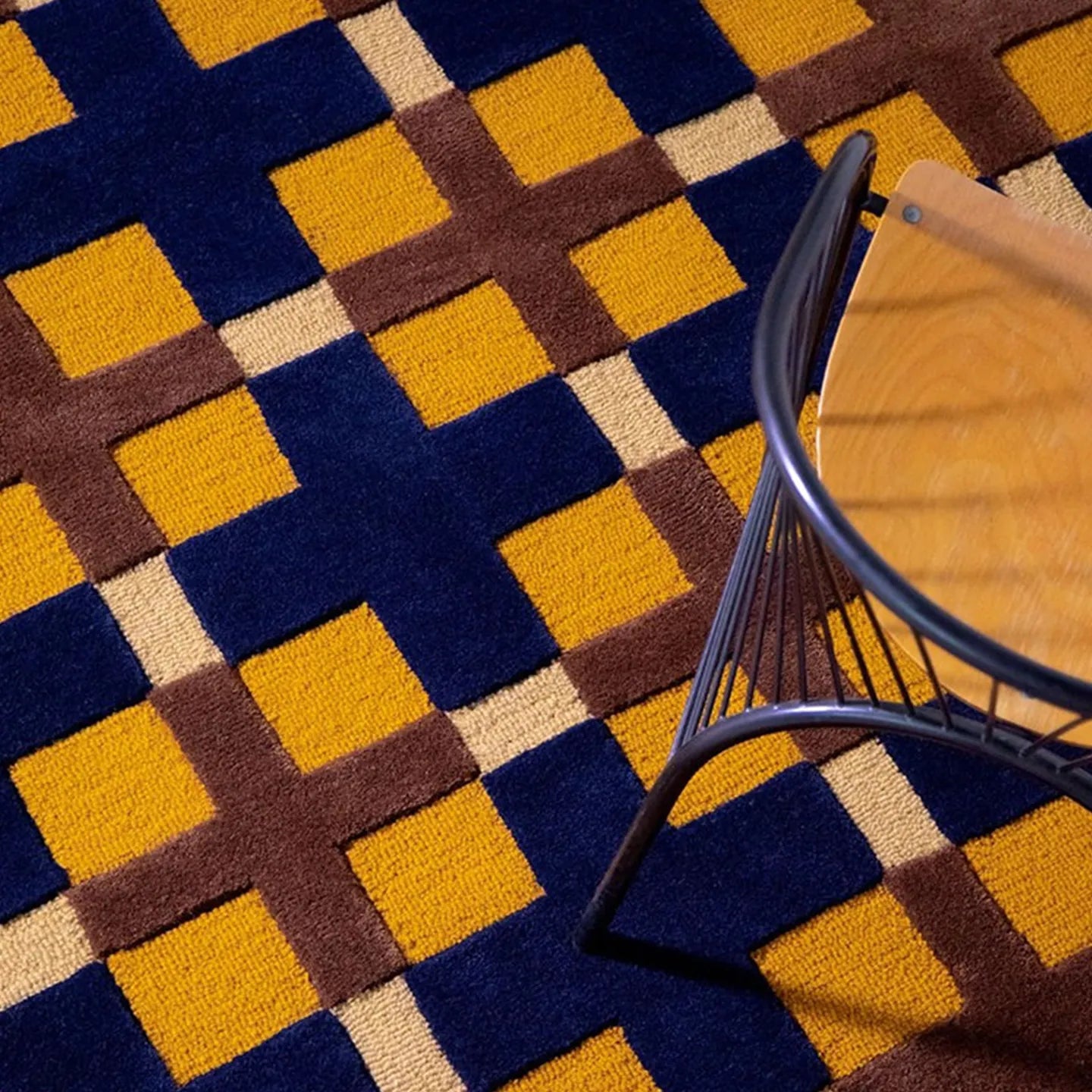 Close-up of the Juno mustard, gold, and navy checkered tufted rug by Housenfriends with a chair on top