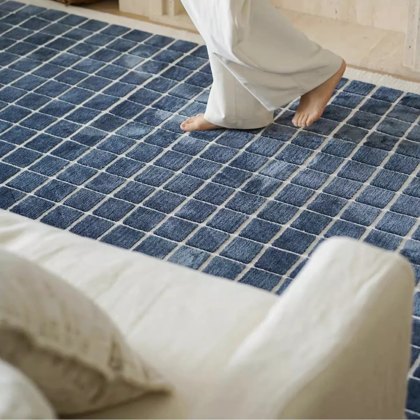 Salina navy blue checkered modern rug by Housenfriends with a person walking on it.