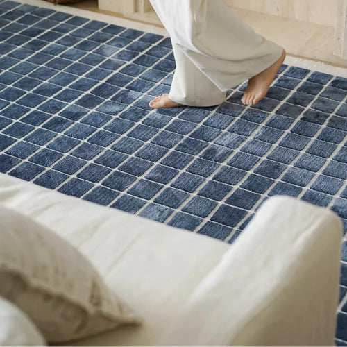 Salina navy blue checkered modern rug by Housenfriends with a person walking on it.