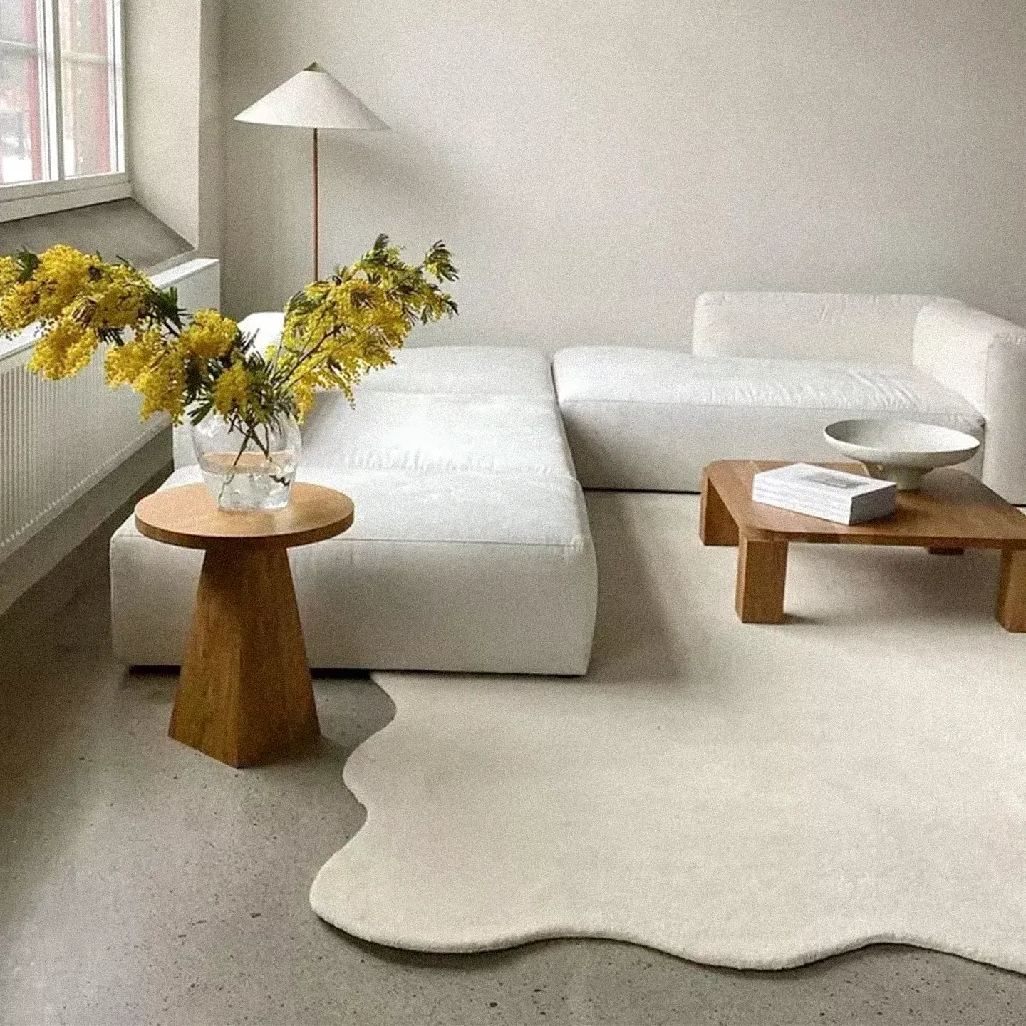 Cora off-white irregular wavy minimalist rug by Housenfriends in a living room with white sofa and wooden side table