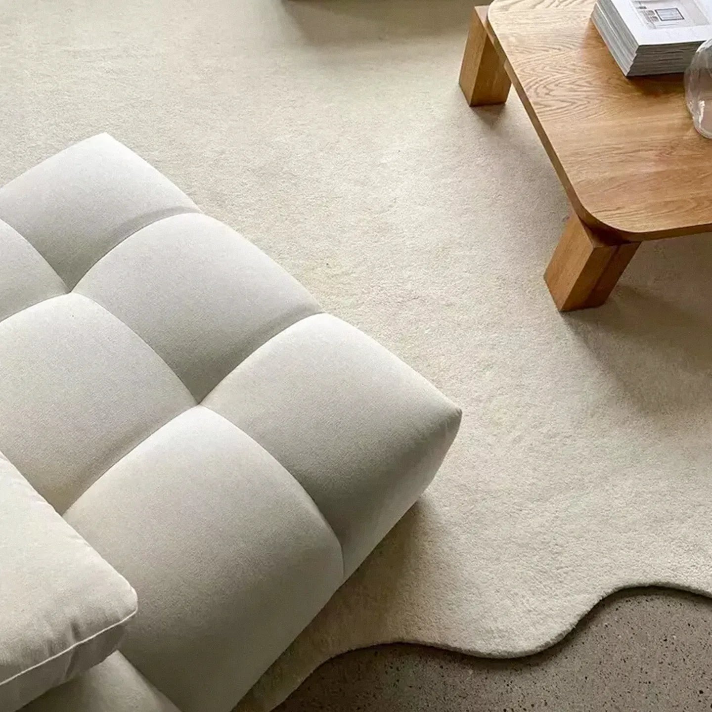 A living room with light gray sofa and wooden coffee table, with the Cora off-white irregular wavy rug by Housenfriends