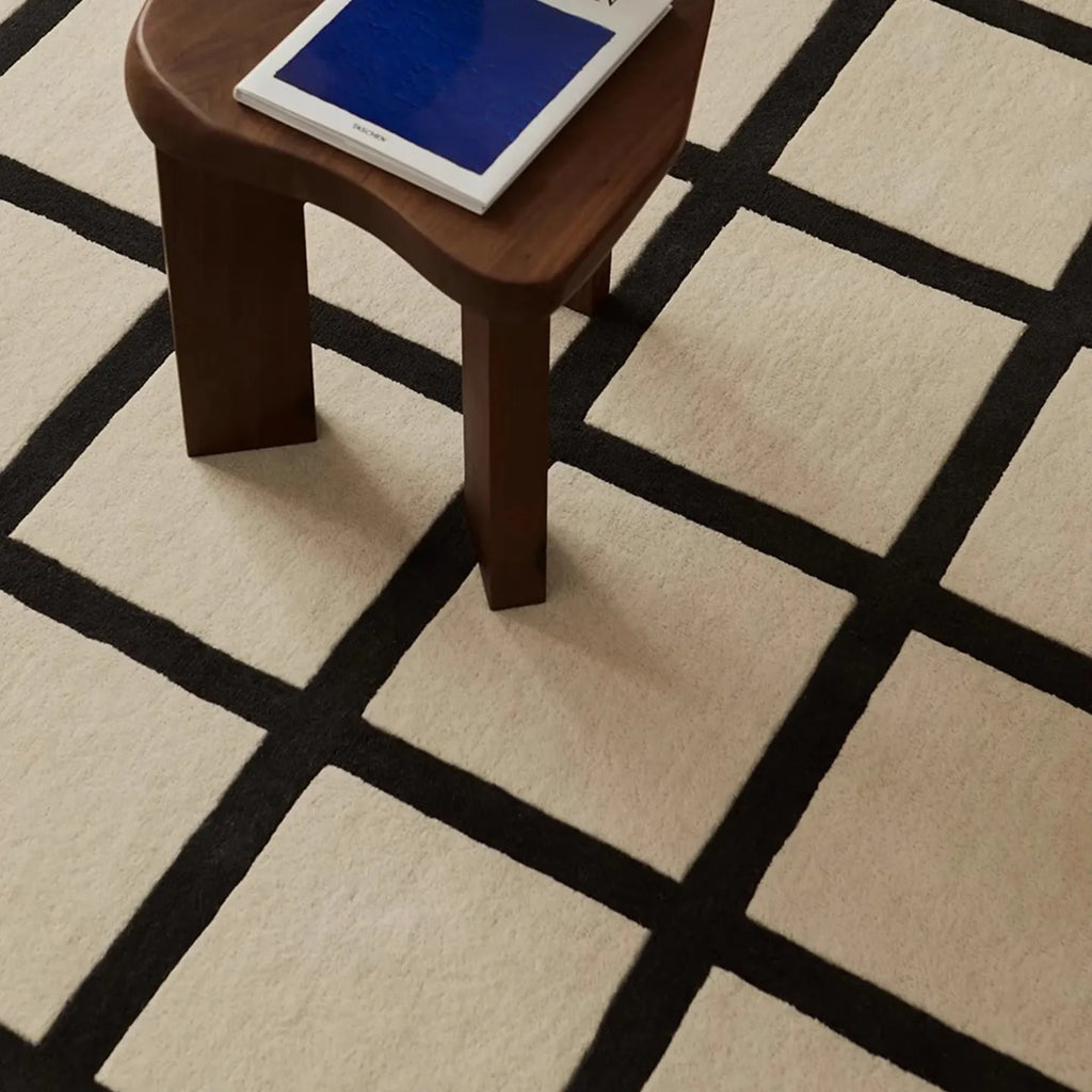 Wooden stool with a blue cushion on Studio Black and Cream Modern Grid Cut Pile Rug by Housenfriends
