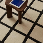 Wooden stool with a blue cushion on Studio Black and Cream Modern Grid Cut Pile Rug by Housenfriends