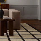 Living room with a beige sofa, wooden side table, and Studio Black and Cream Checkered Cut Pile Rug by Housenfriends