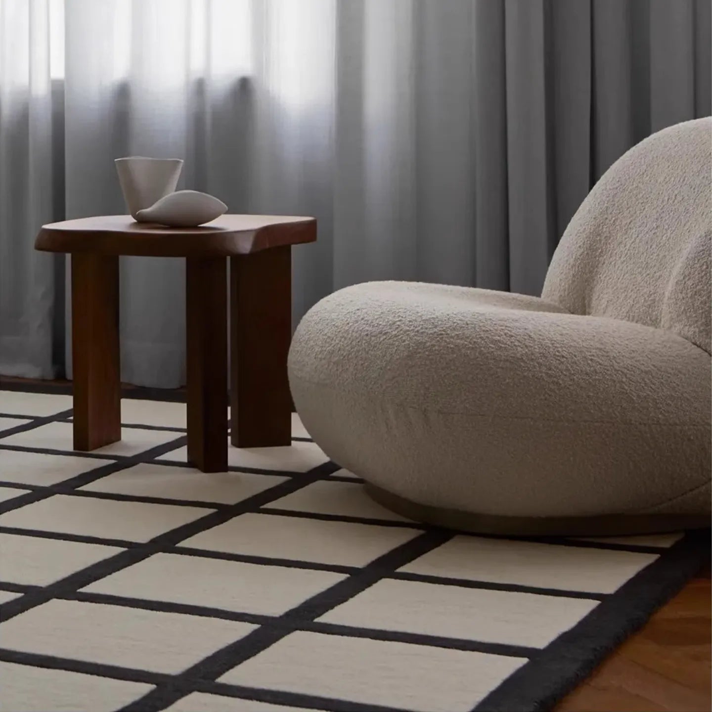 Beige armchair next to a wooden side table on a Black and Cream Checkered Cut Pile Rug by Housenfriends