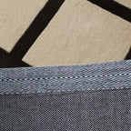Close-up of a textured fabric backing of Studio Black and Cream Checkered Cut Pile Rug by Housenfriends