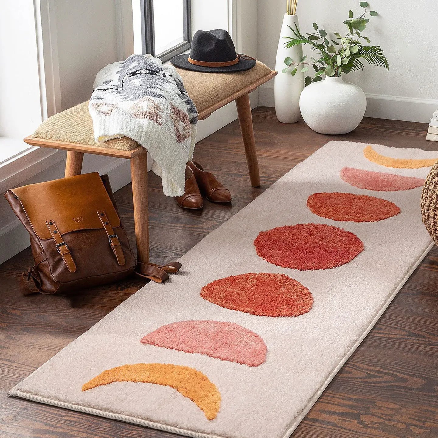 Eclipse pink and orange semi-circle shaggy runner rug by Housenfriends on wooden floor with bench and backpack