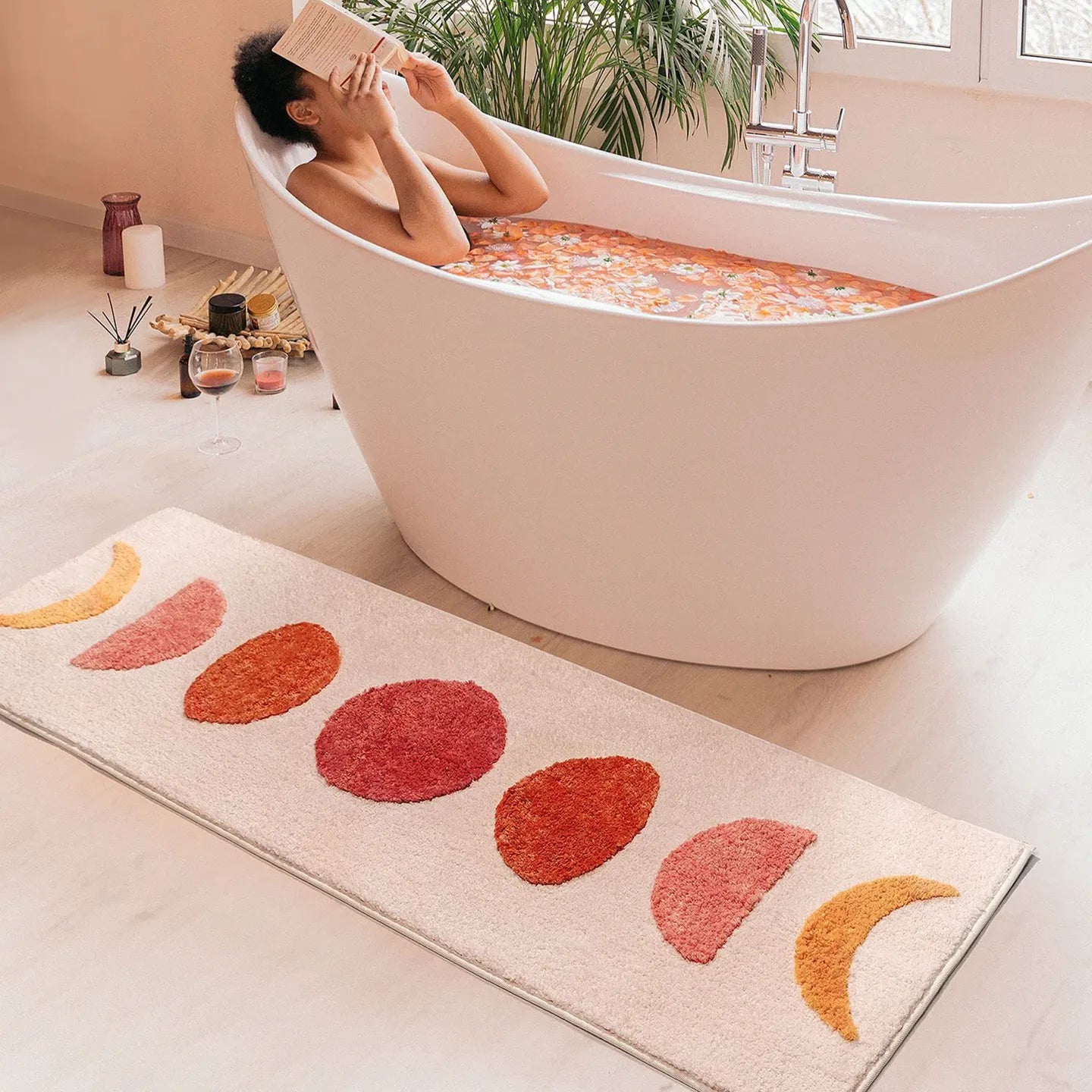 Eclipse pink and orange semi-circle shaggy runner rug by Housenfriends on bathroom floor with person reading in bathtub