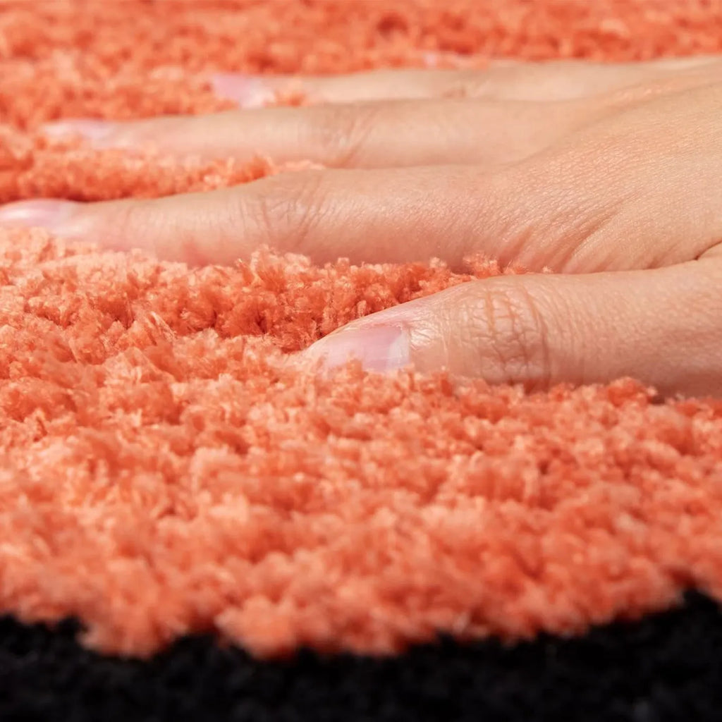 Close-up of hand on hand-tufted orange surface of Housenfriends runner rug