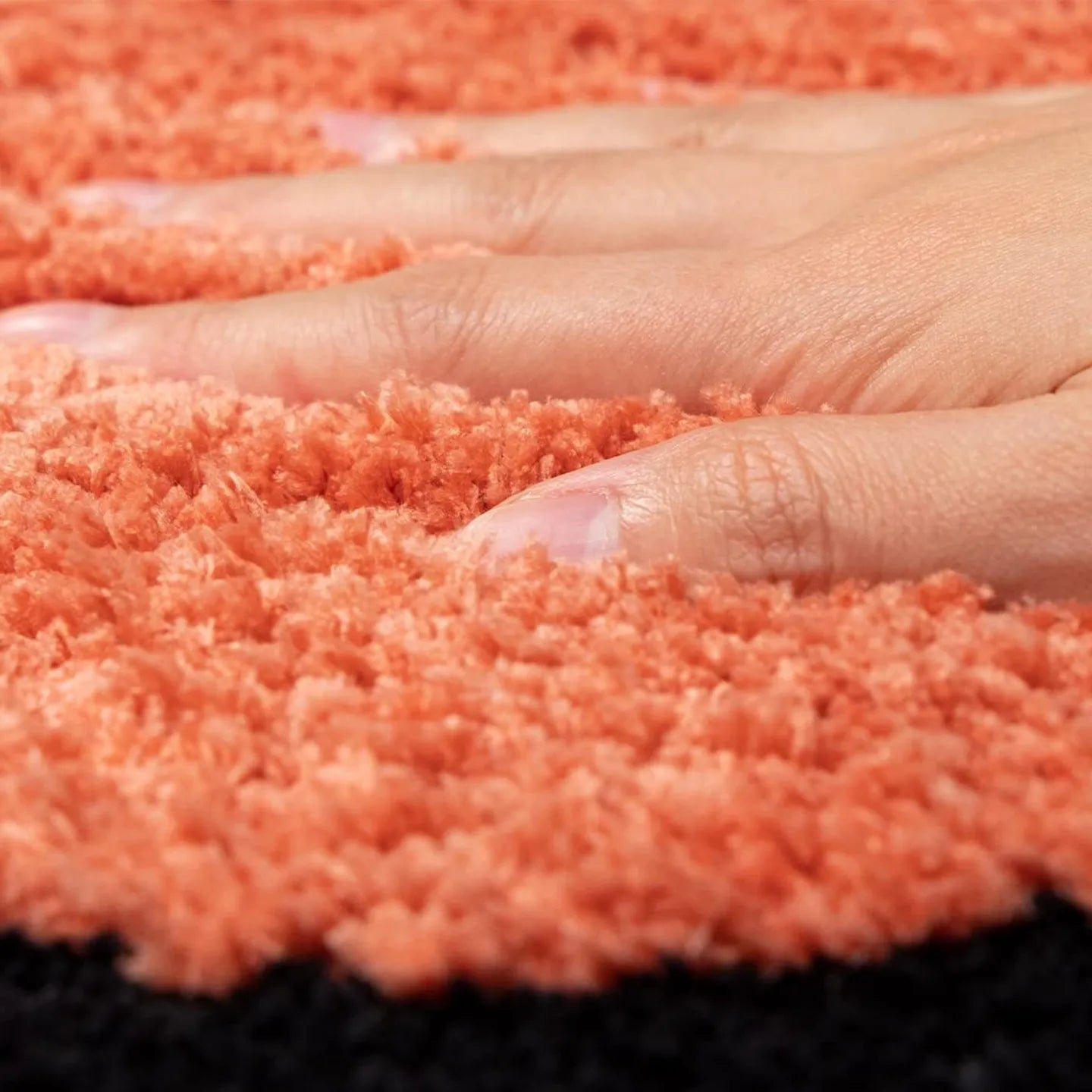 Close-up of hand on hand-tufted orange surface of Housenfriends runner rug