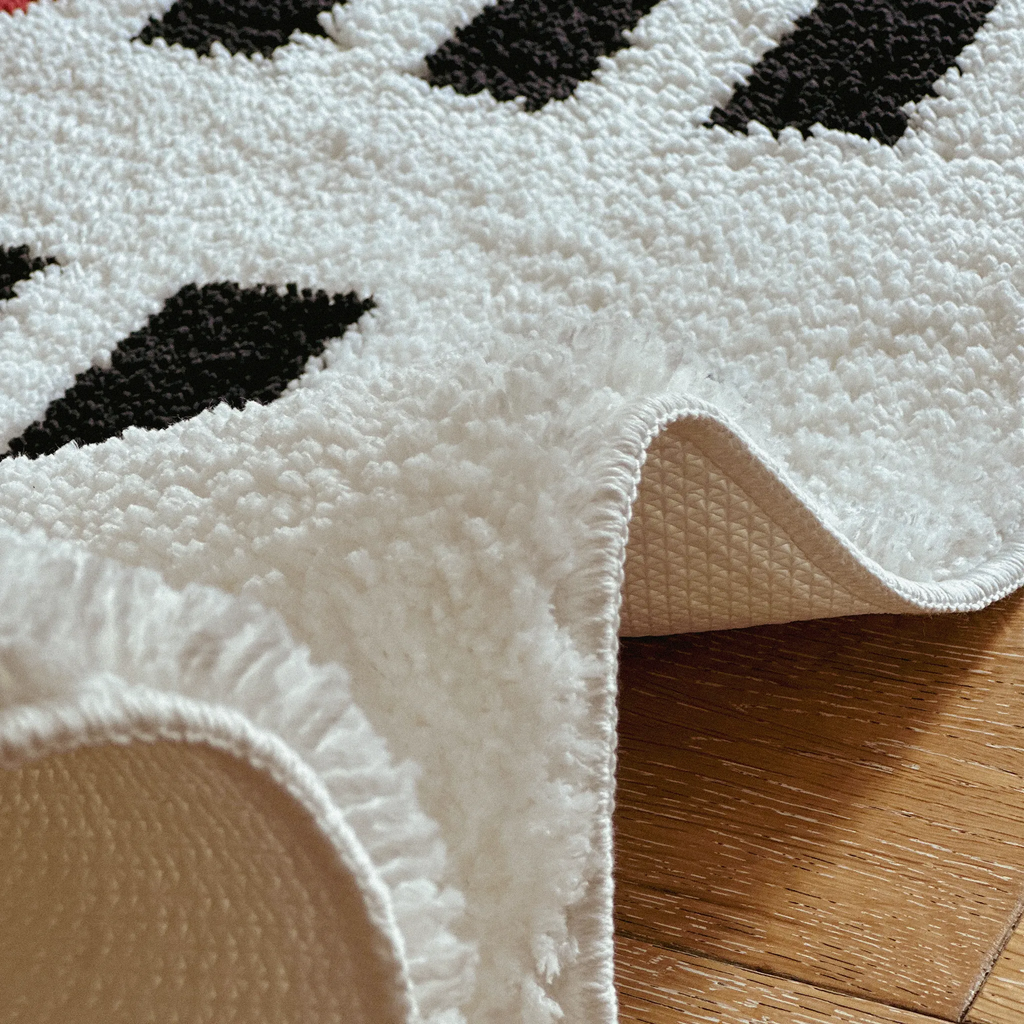 Close-up of the fabric of Arlo White and Black Checkered Tufted Runner Rug on a wooden floor.