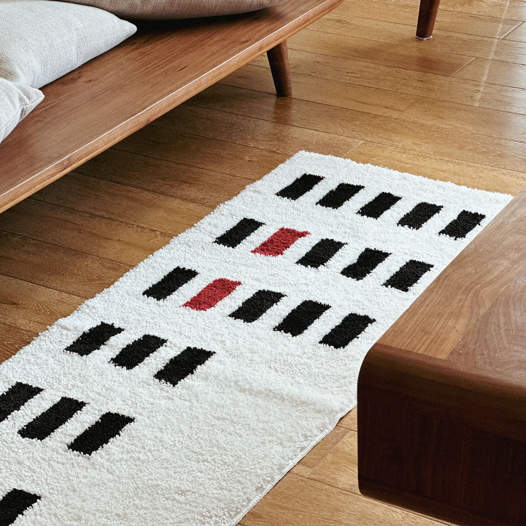 Arlo White and Black Asymmetric Checkered Tufted Runner Rug by Housenfriends on a wooden floor