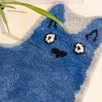 Close-up of Goofy Wide Eyed Blue Cat Shaped Tufted Rug on a light background