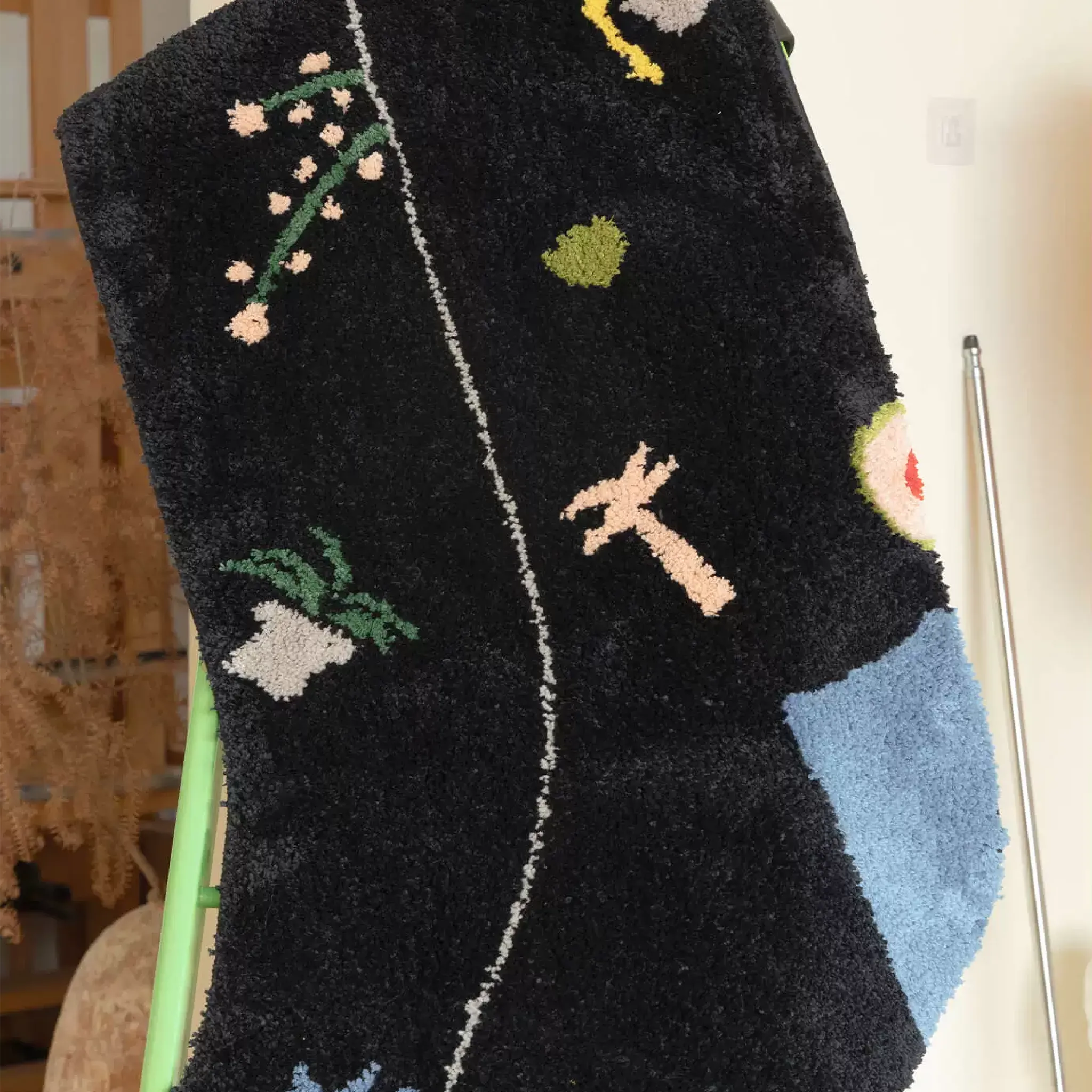 Black graphic motif sock shaped rug close up with raised flower sprig, palm tree and pale blue heel patch by Housenfriends